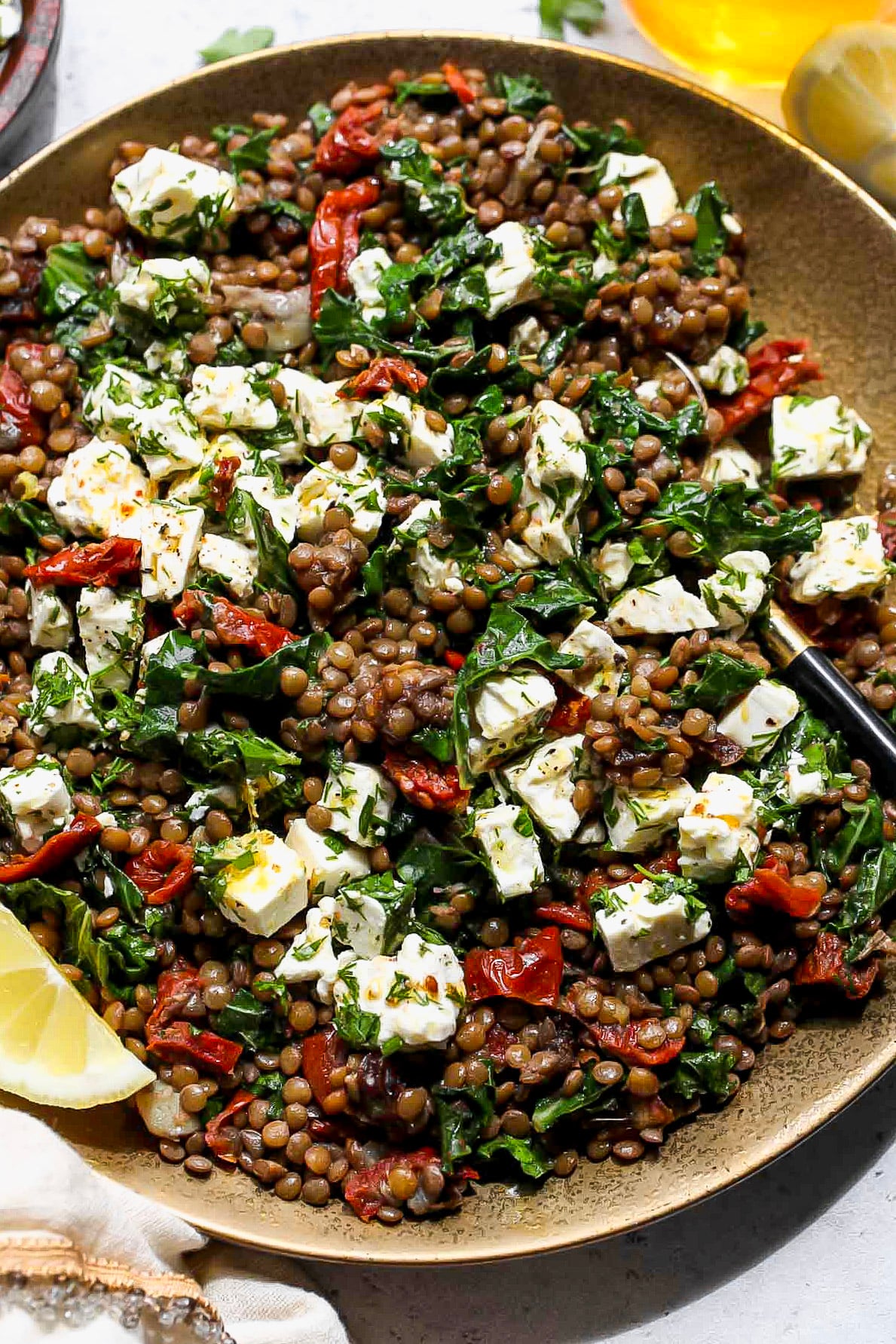 Warm Lentil Salad with Feta scattered overtop styled on a gold plate.