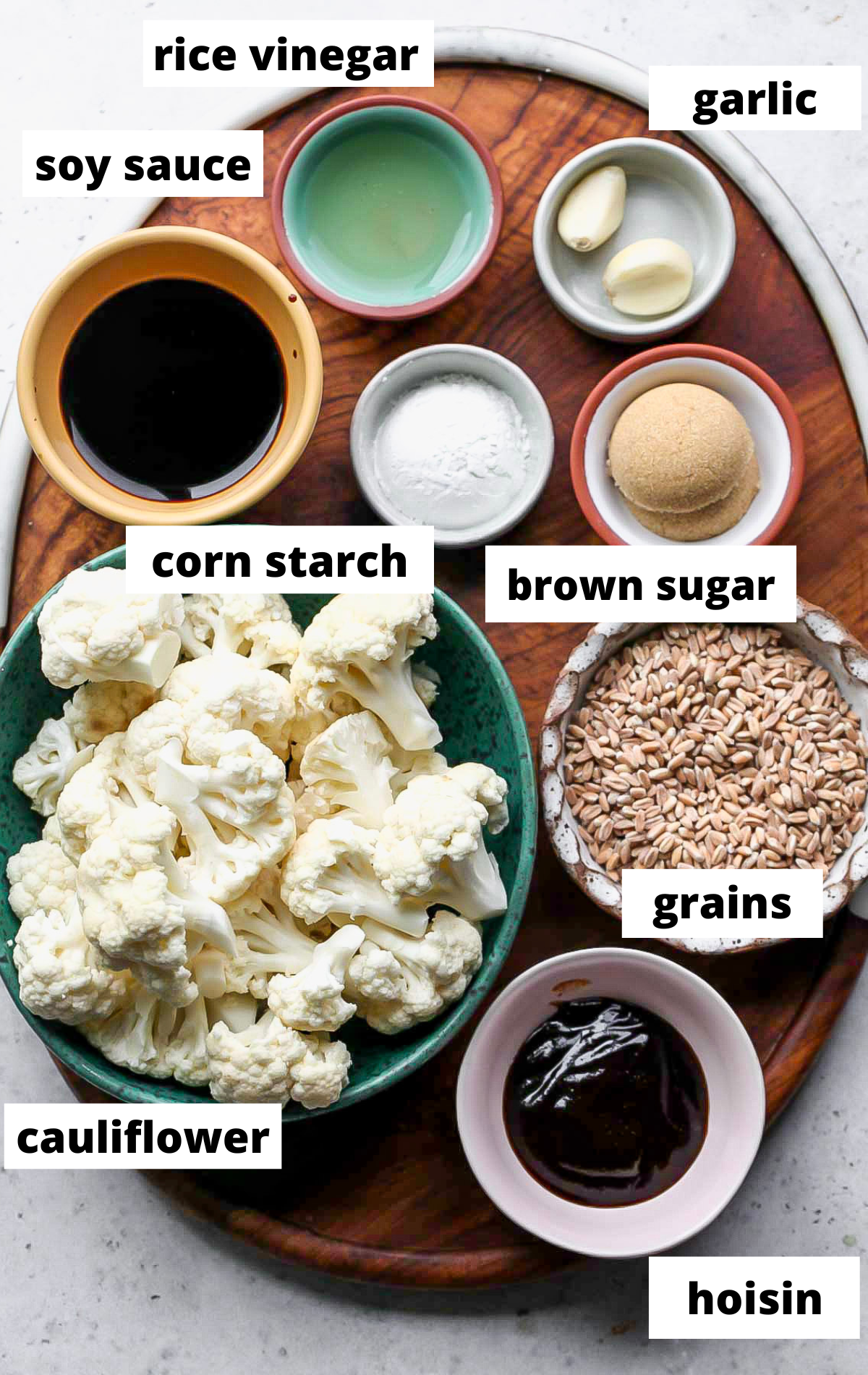 Recipe ingredients in separate bowls with labels on a wooden tray.