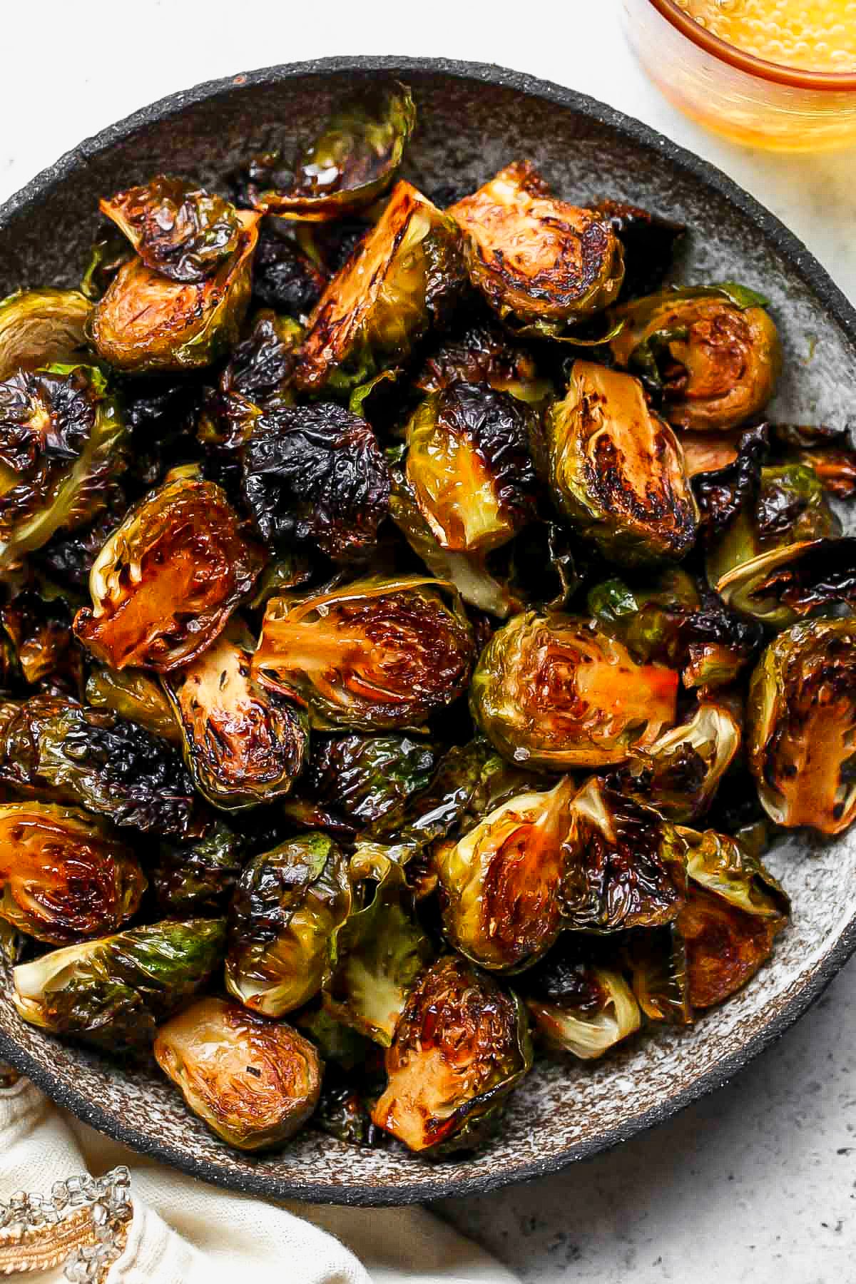 Silver bowl filled with roasted balsamic Brussels sprouts.