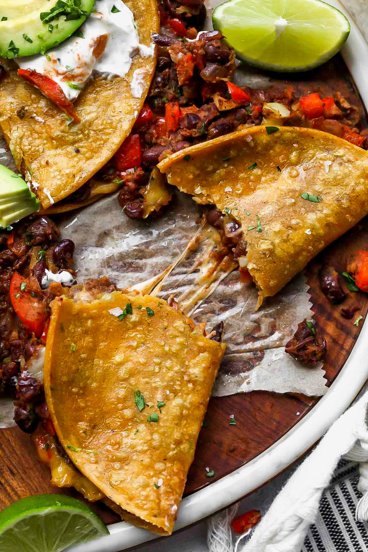 A black bean taco being pulled apart to show cheesy filling.