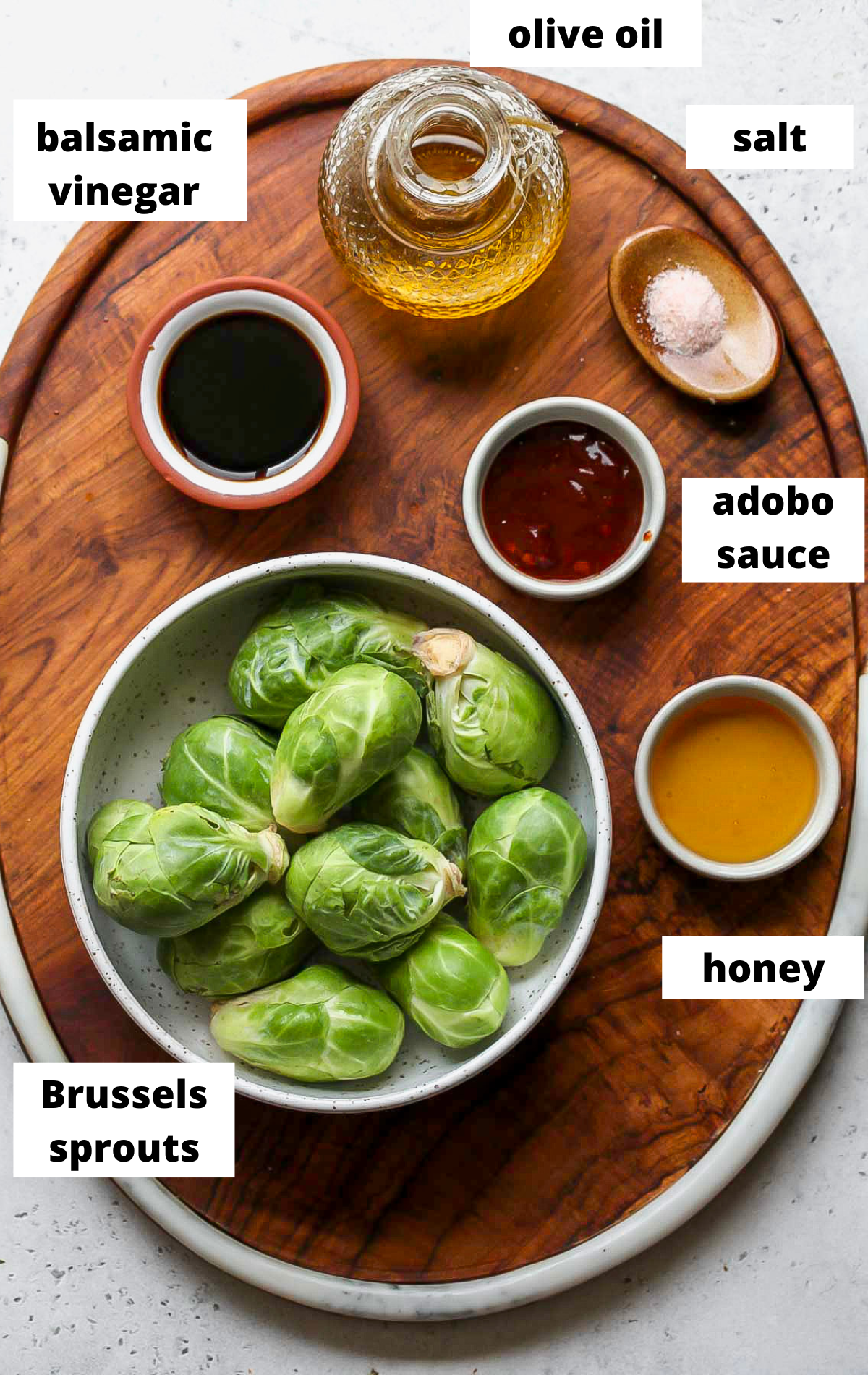 Recipe ingredients in separate bowls on a wooden tray with labels.