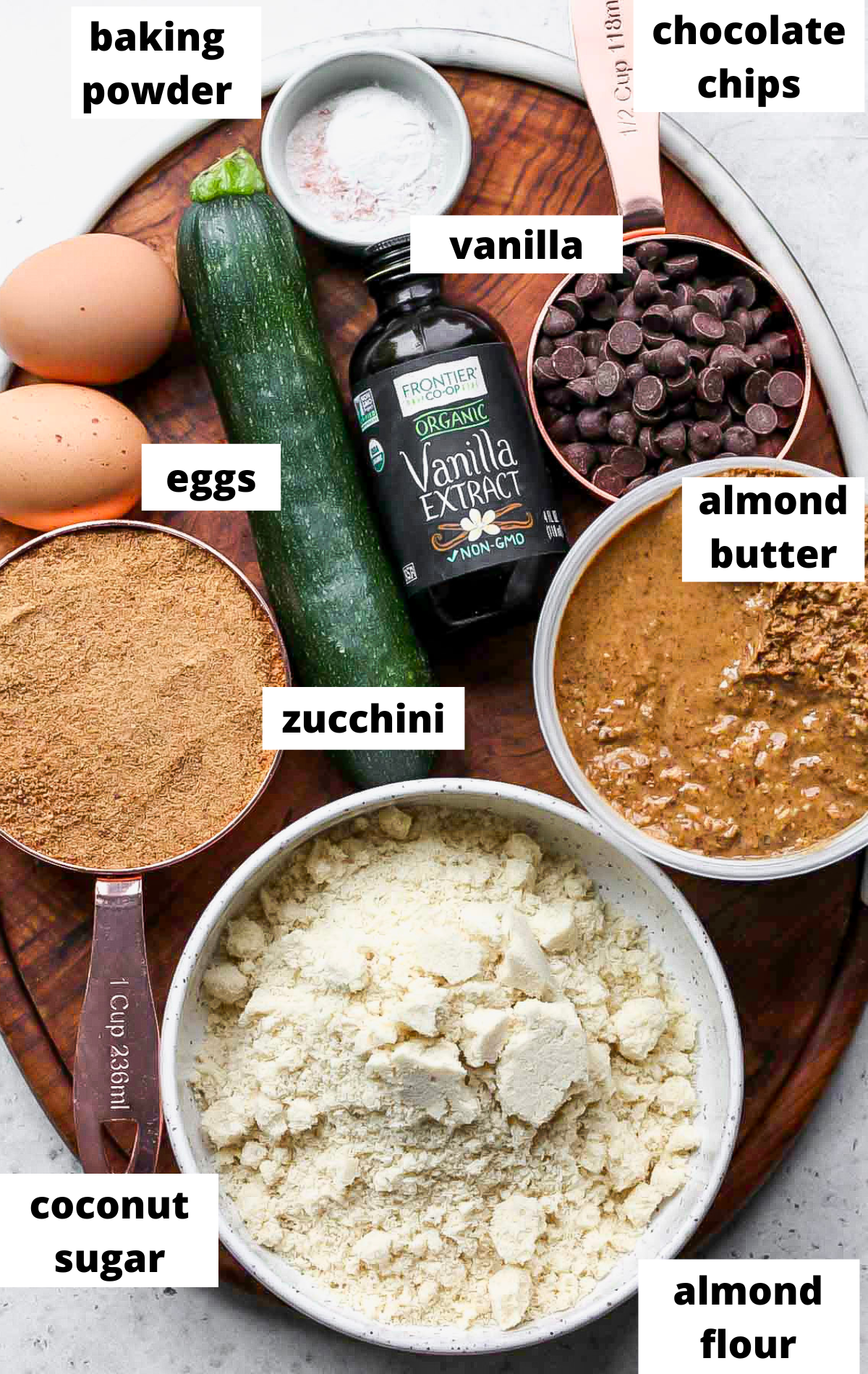 Recipe ingredients in separate bowls with labels on a wooden serving platter.