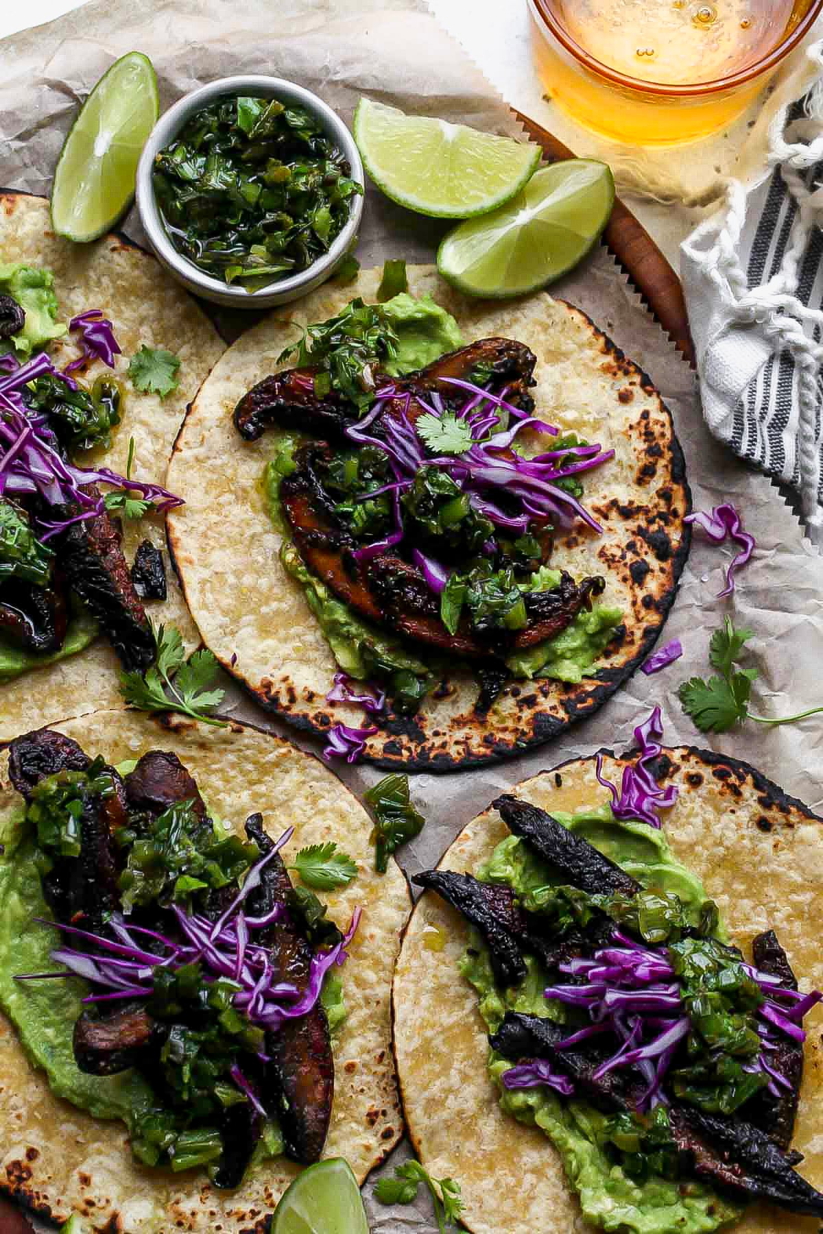 Four mushroom tacos being assembled on a large wooden serving platter.