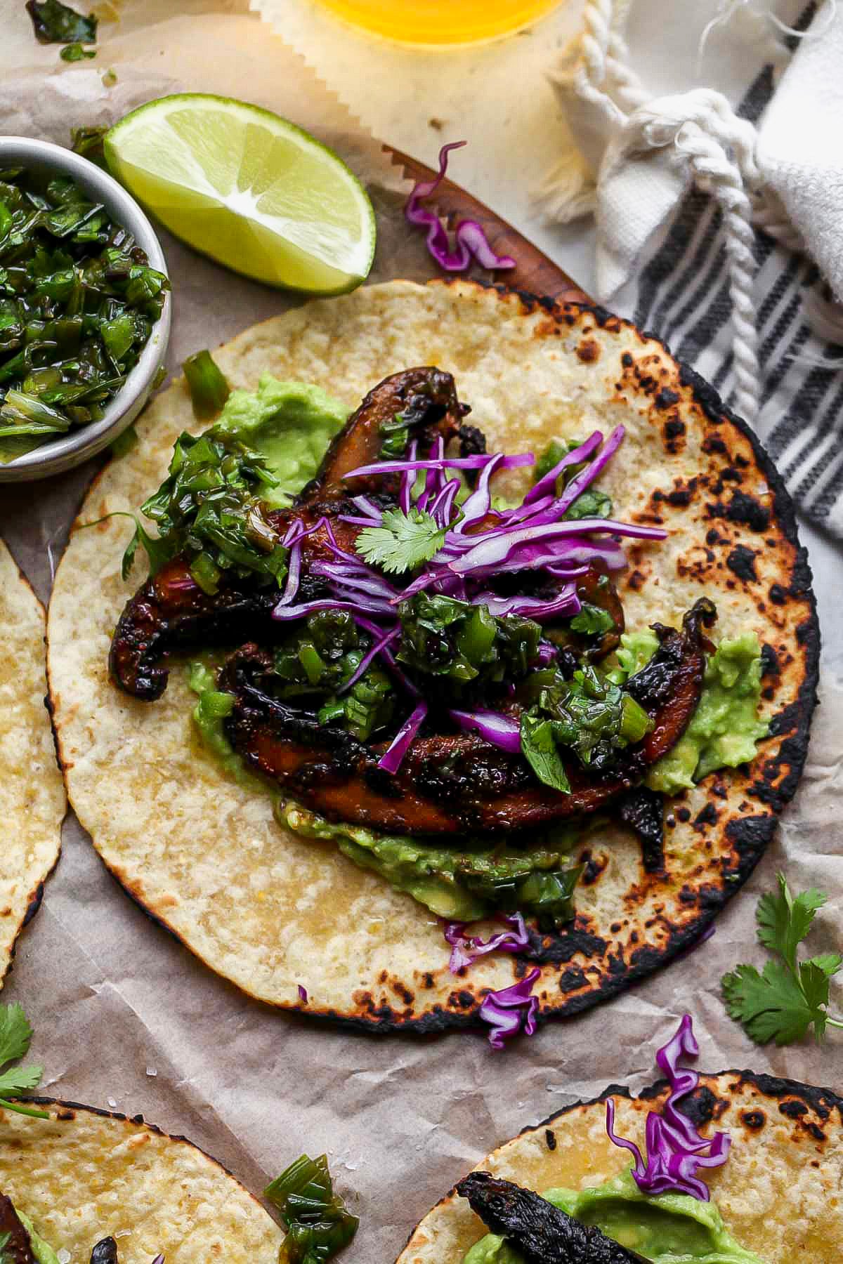 Portobello tacos arranged on a serving platter topped with charred scallion salsa verde.