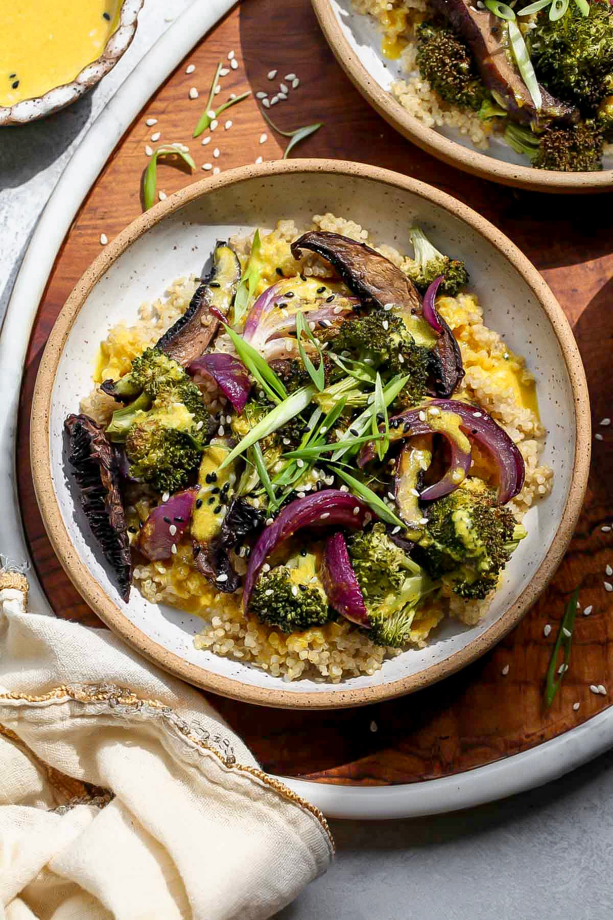 Roasted veggie quinoa bowl in a white bowl on top of a wooden serving tray.