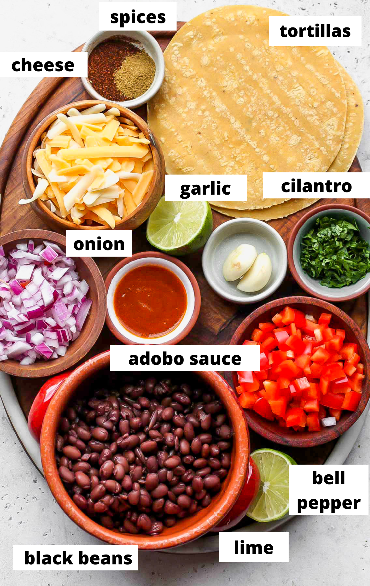 Recipe ingredients in separate bowls with labels on a serving board.