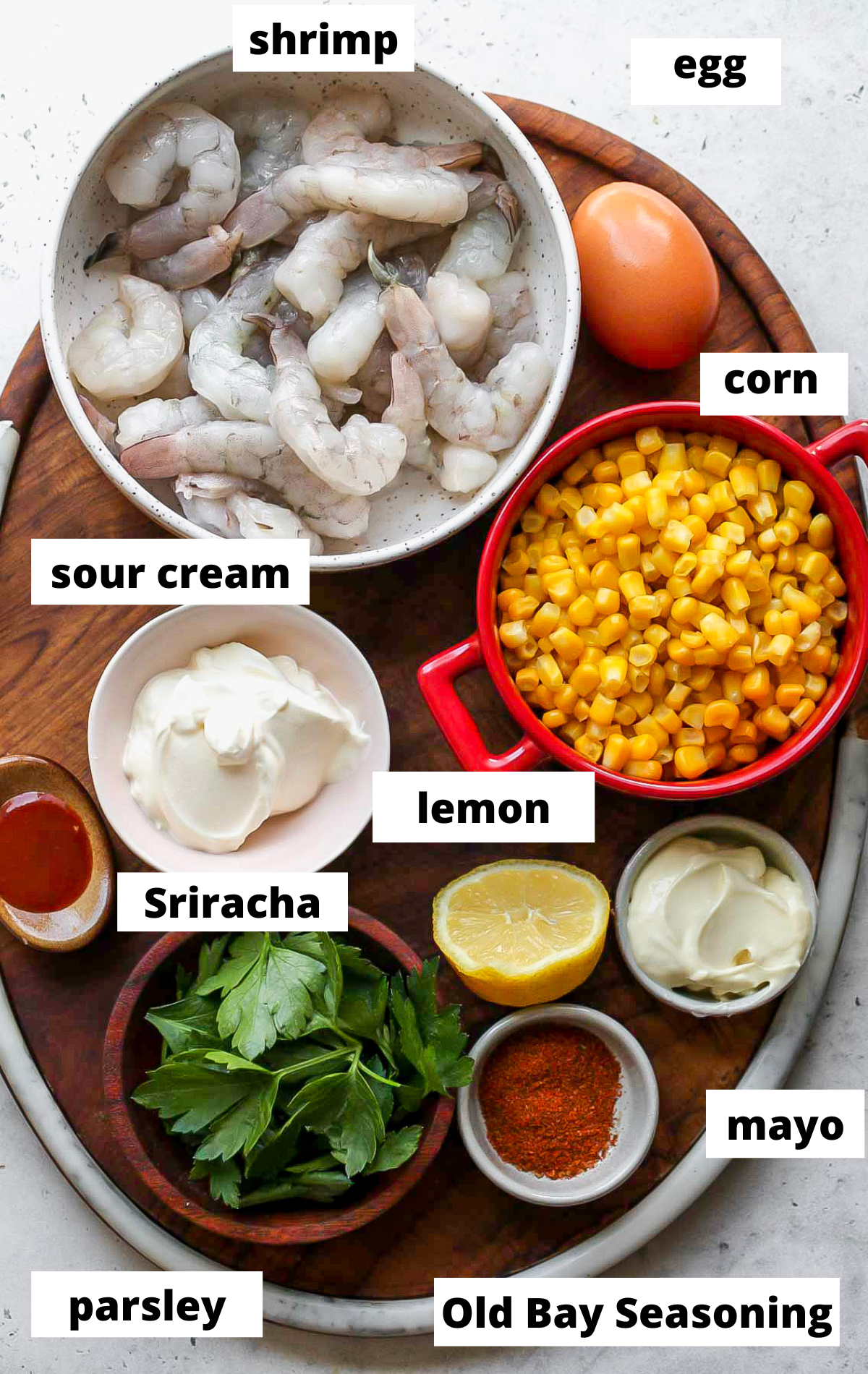 Recipe ingredients in separate bowls on a wooden serving platter with labels.