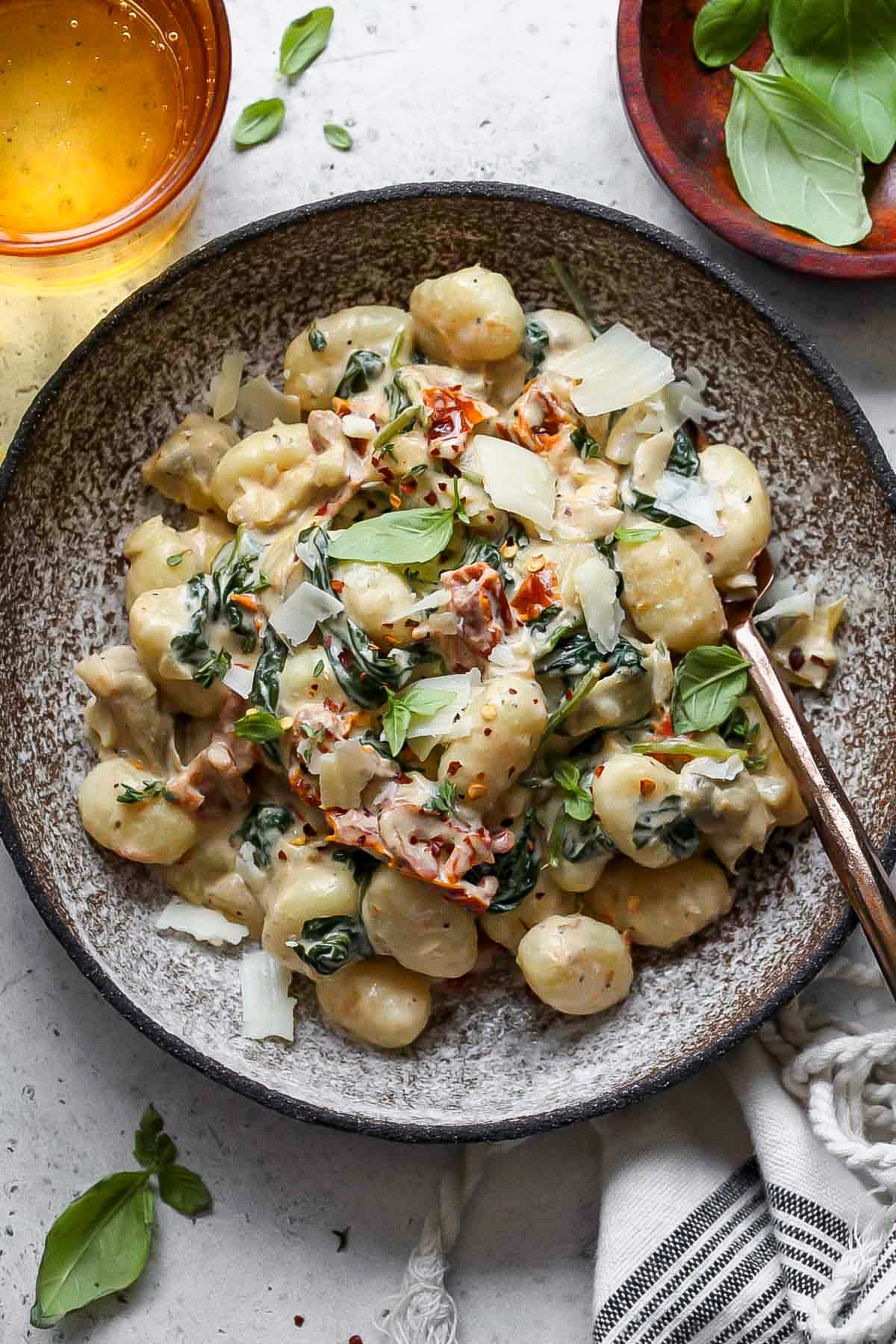 Sun-dried tomato gnocchi in a grey serving bowl with a fork resting on the right side.