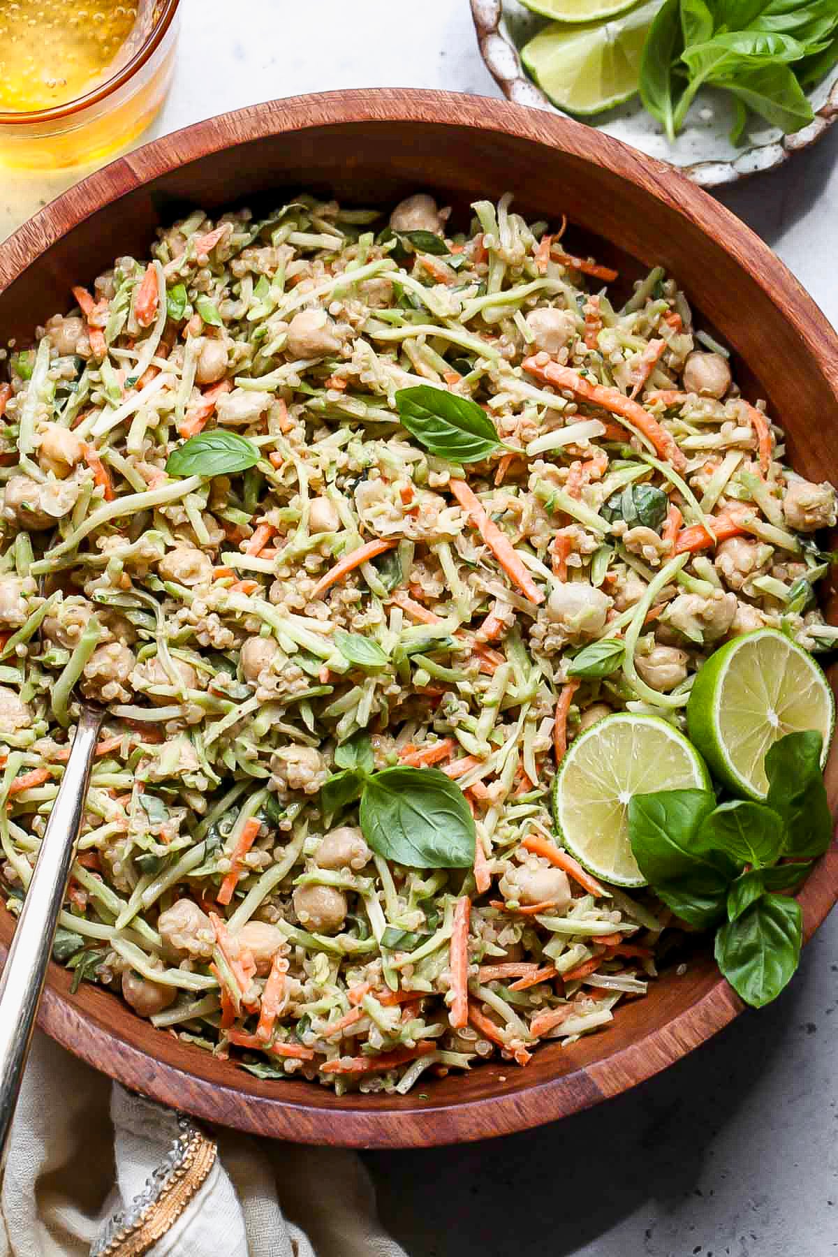 Thai broccoli chickpea salad in a wooden serving bowl topped with lime wedges.