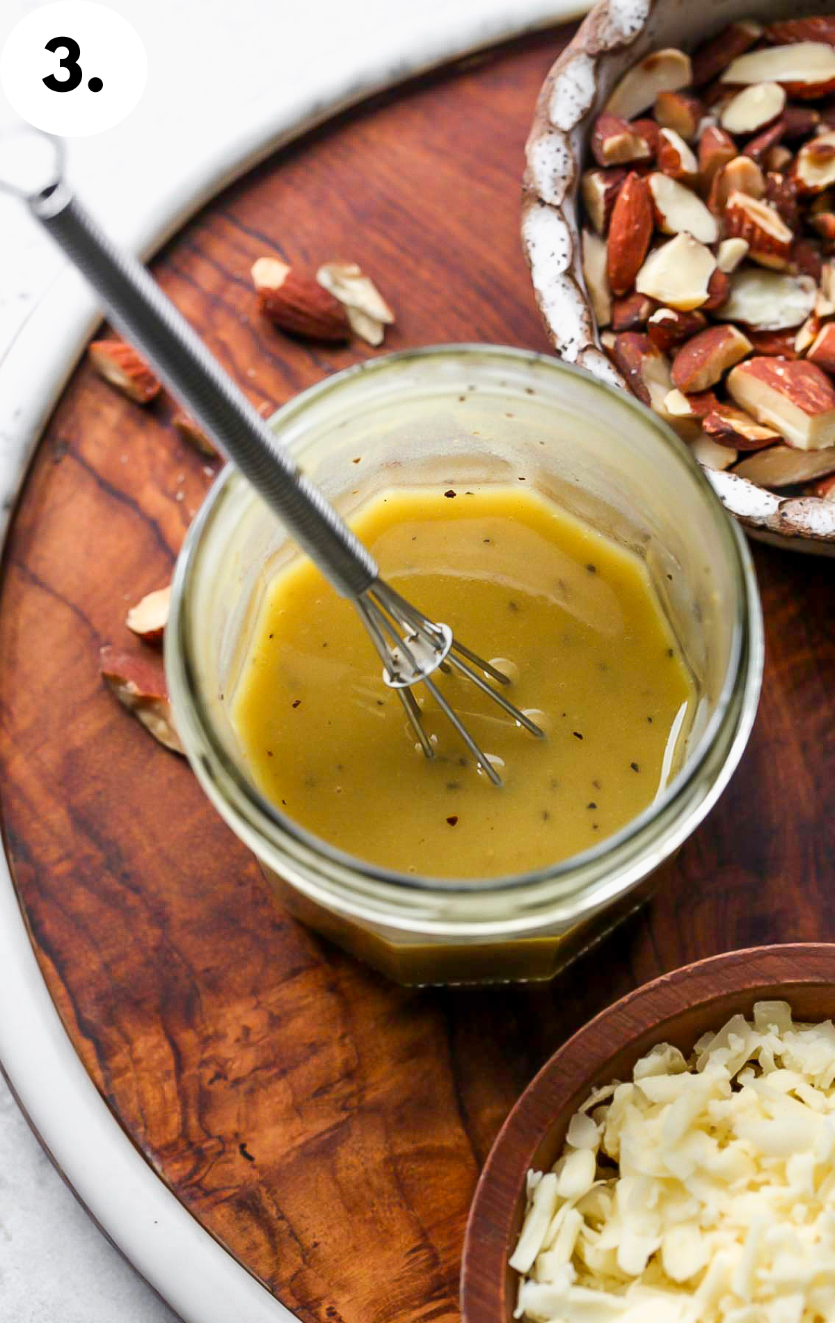Honey-mustard dressing being whisked in a glass jar.