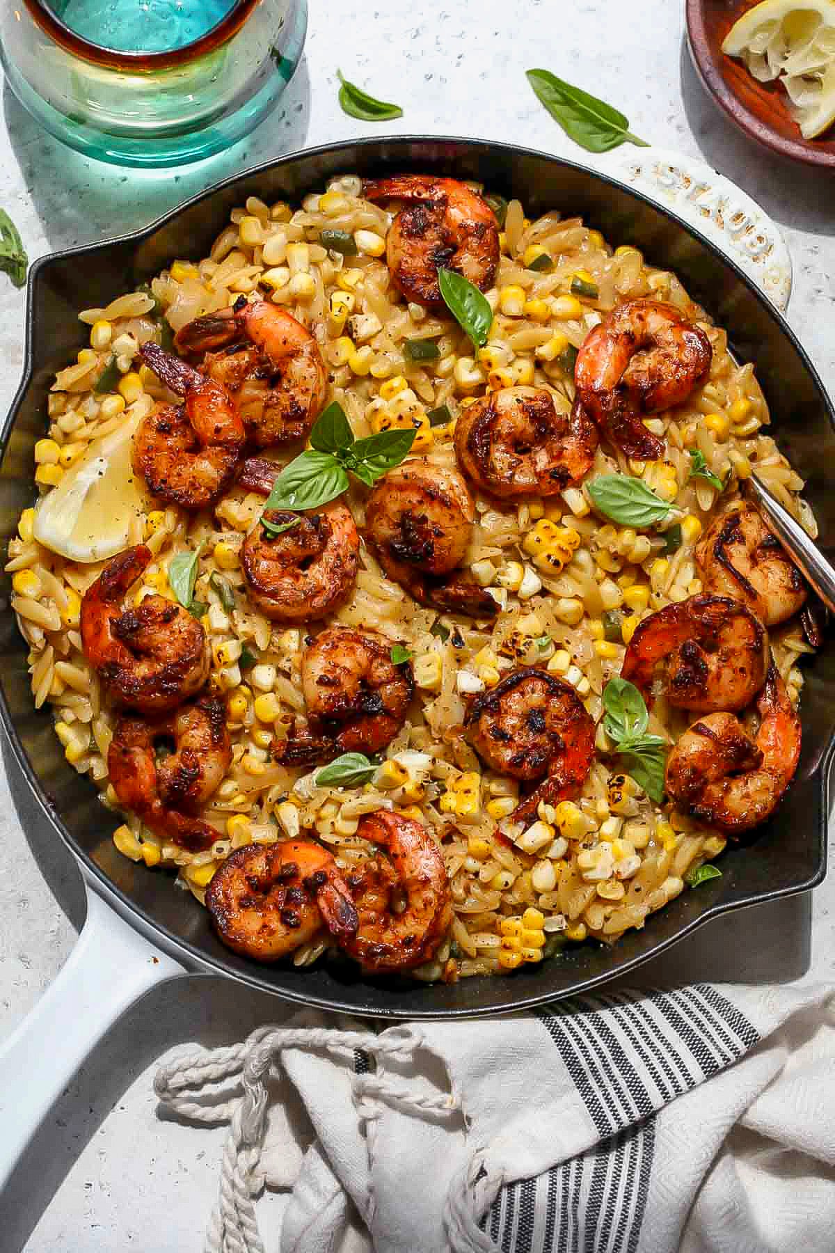 Large white skillet filled with creamed corn shrimp orzo.