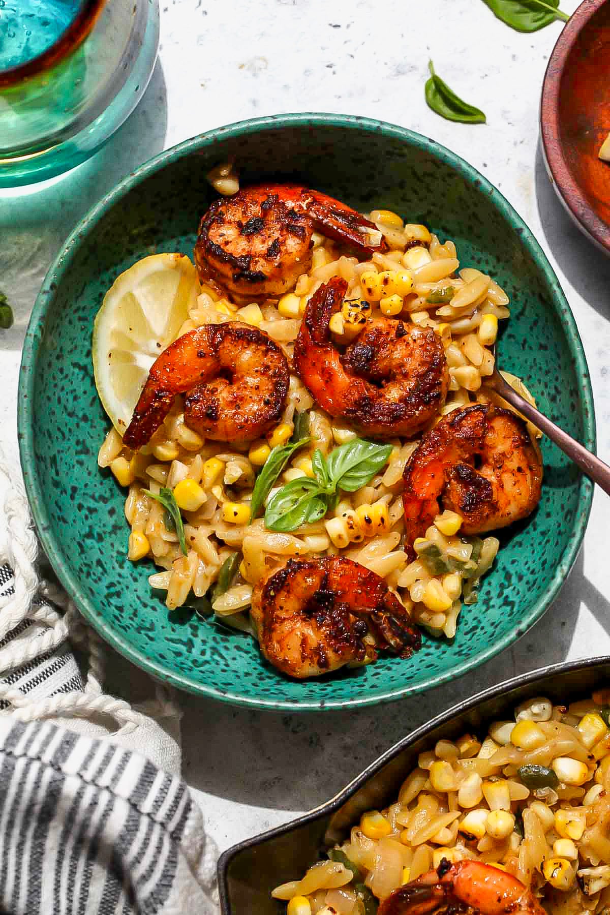 Teal bowl filled with a single serving of creamed corn shrimp orzo.