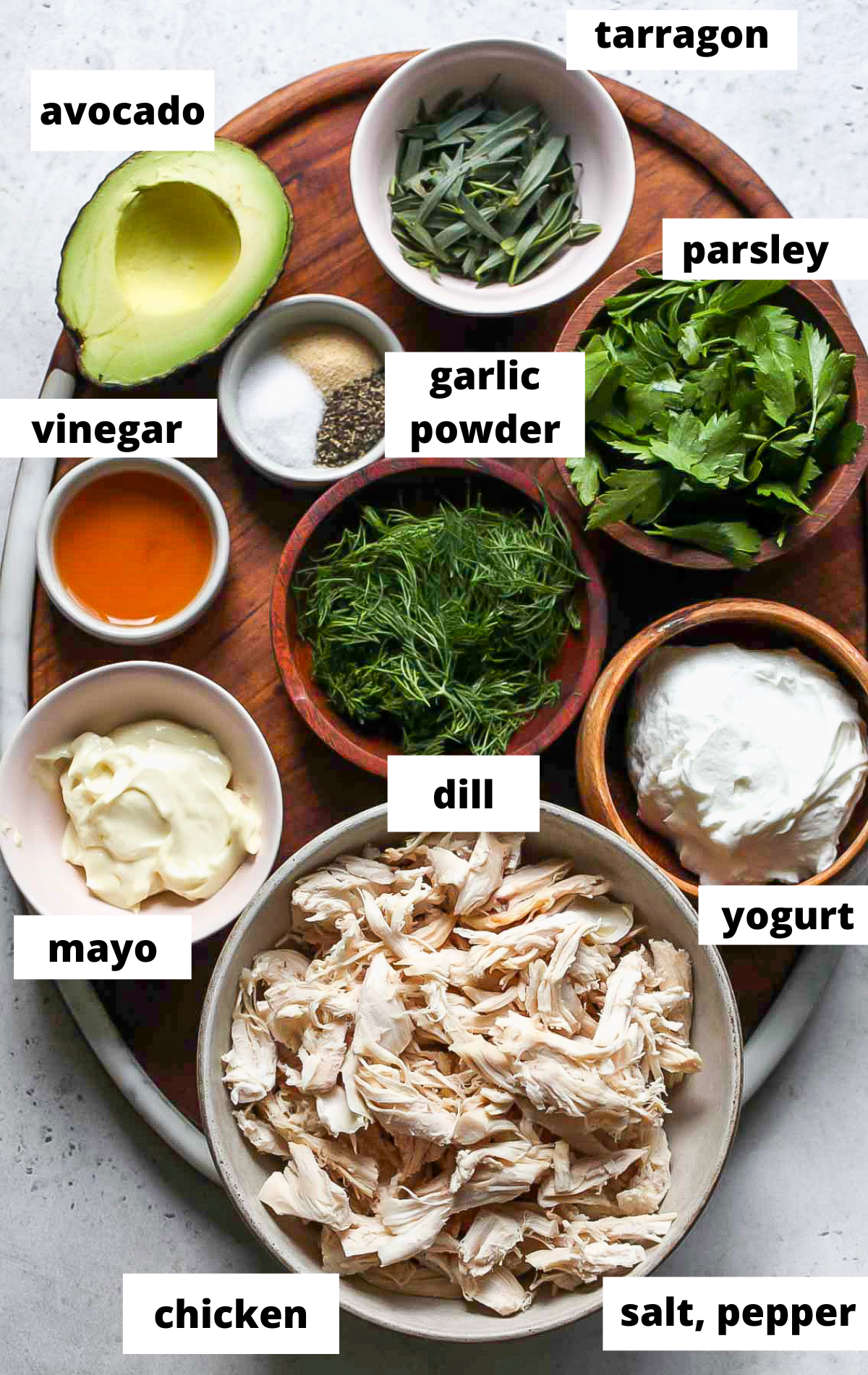 Recipe ingredients in separate bowls on a wooden cutting bored with labels.