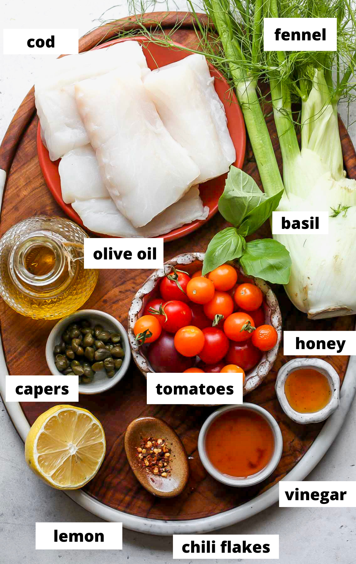 Recipe ingredients in separate bowls with labels on a wooden platter.