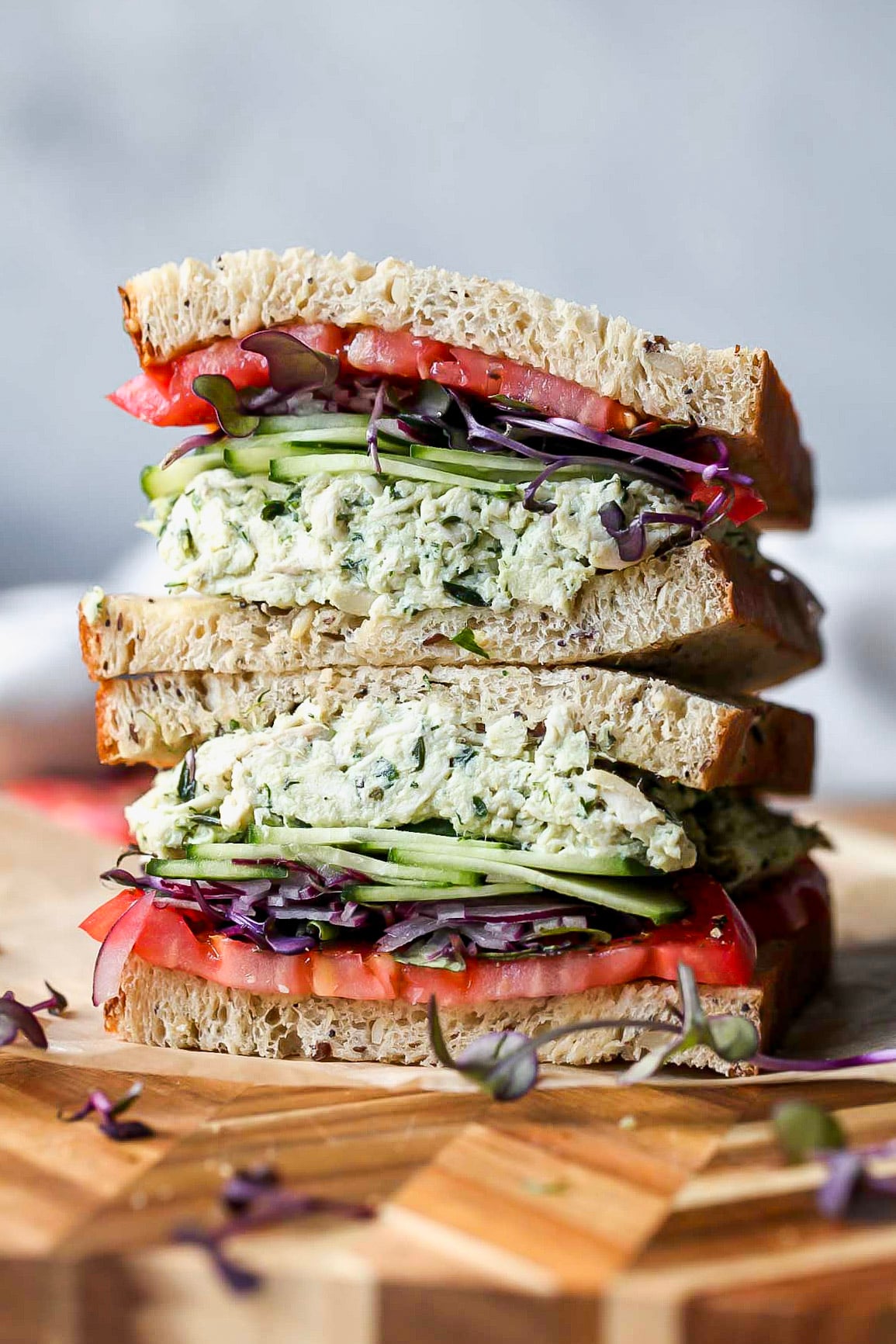Green goddess chicken salad sandwich stacked on a wooden cutting board.