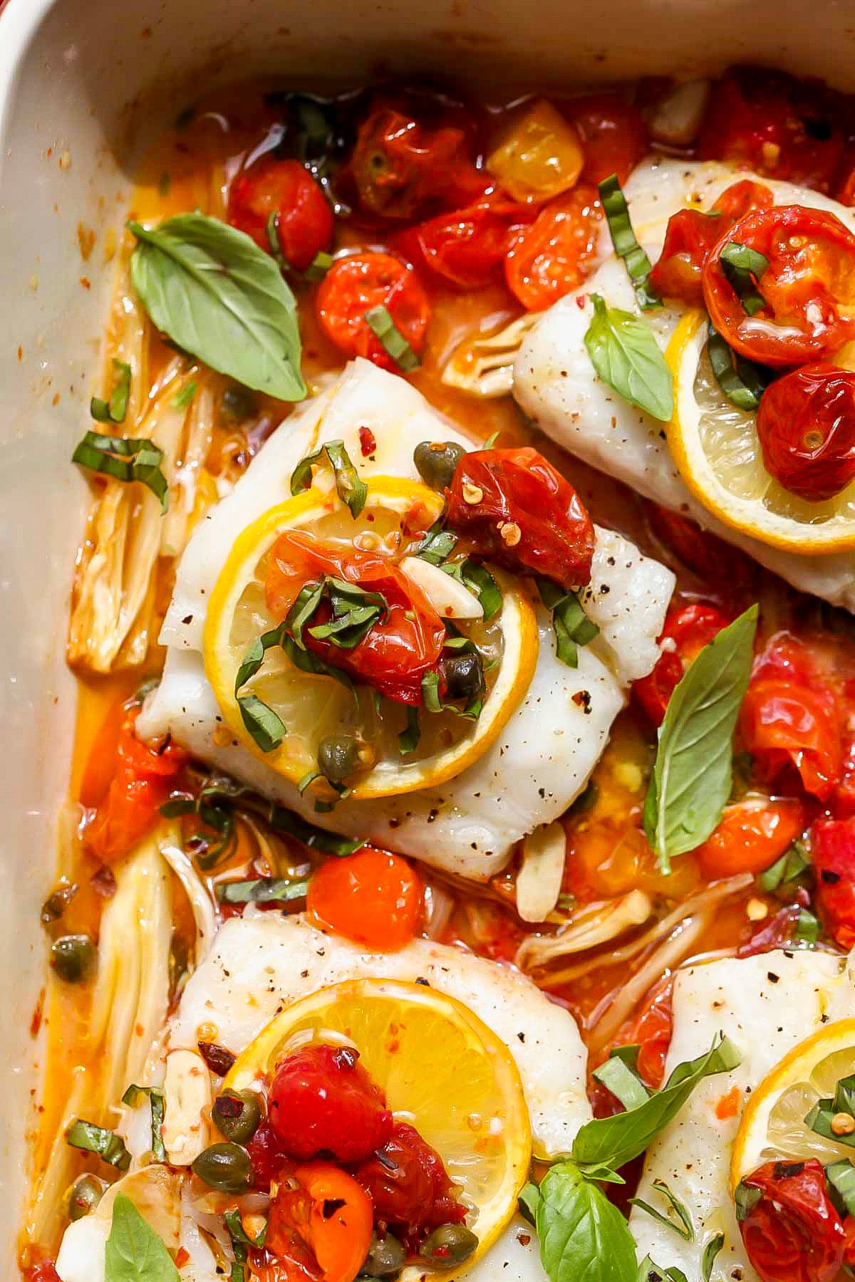 Mediterranean Baked Cod in a baking dish topped with fresh basil.