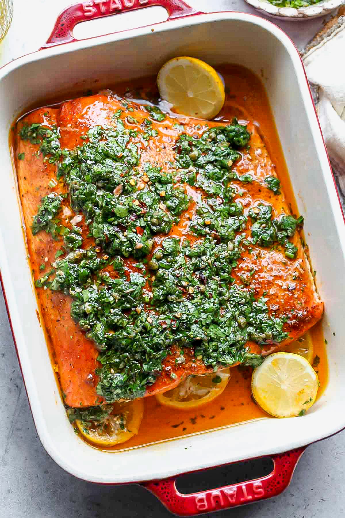Slow roasted salmon salsa verde in a red baking dish.