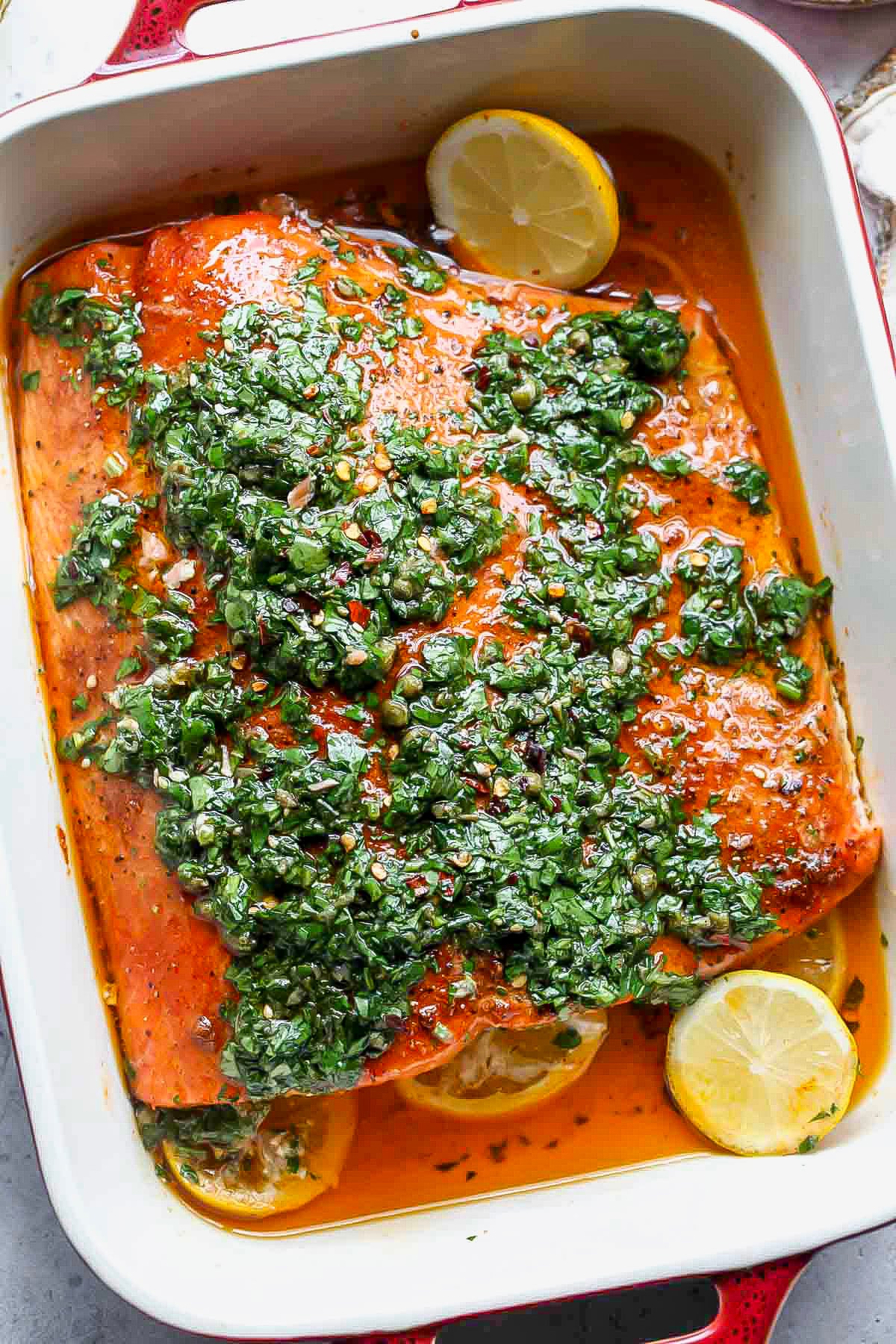 Salsa verde being spooned over cooked salmon.