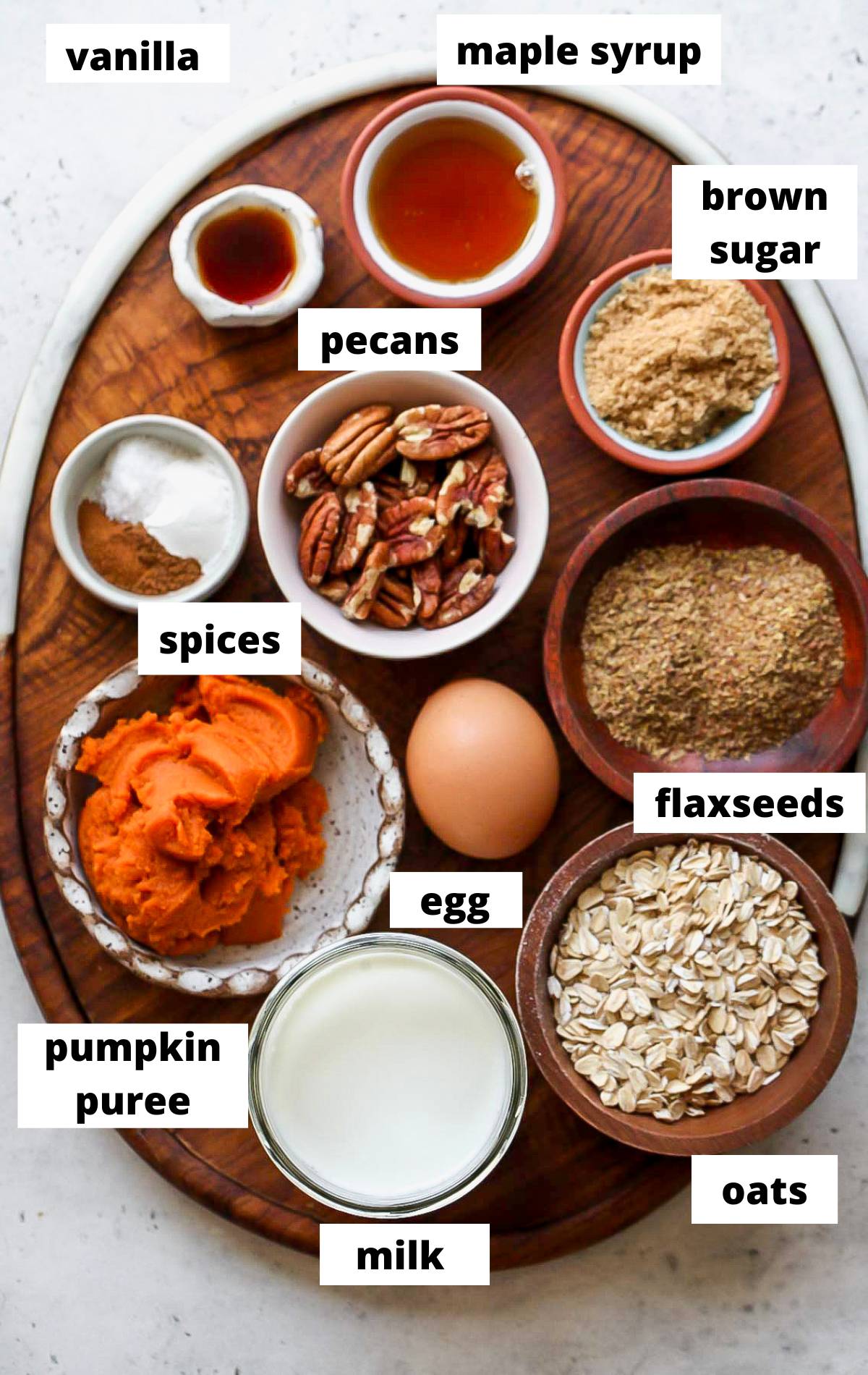 Recipe ingredients in separate bowls with labels on a wooden platter.