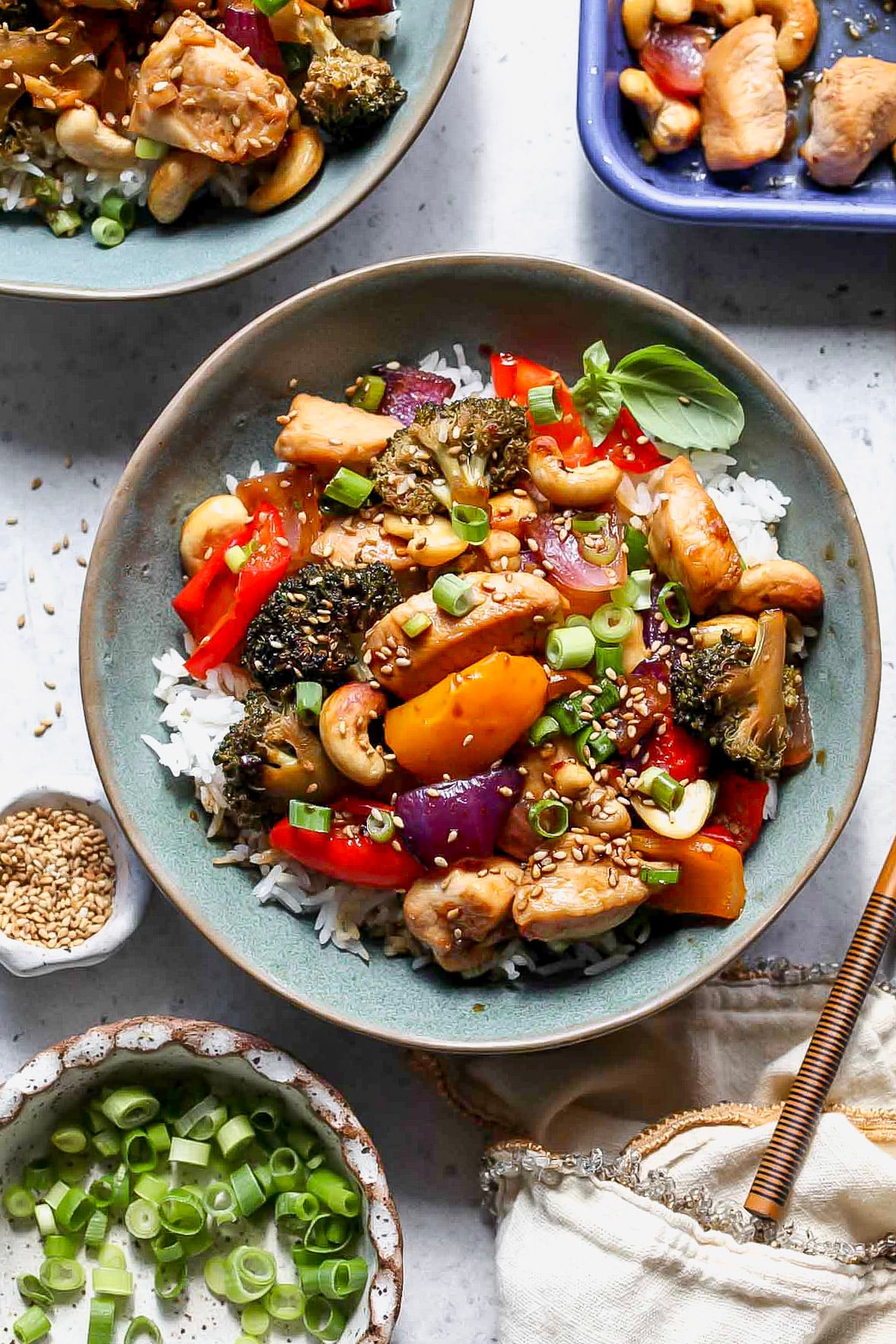 Honey-sesame chicken and veggies served over rice in a blue serving bowl.