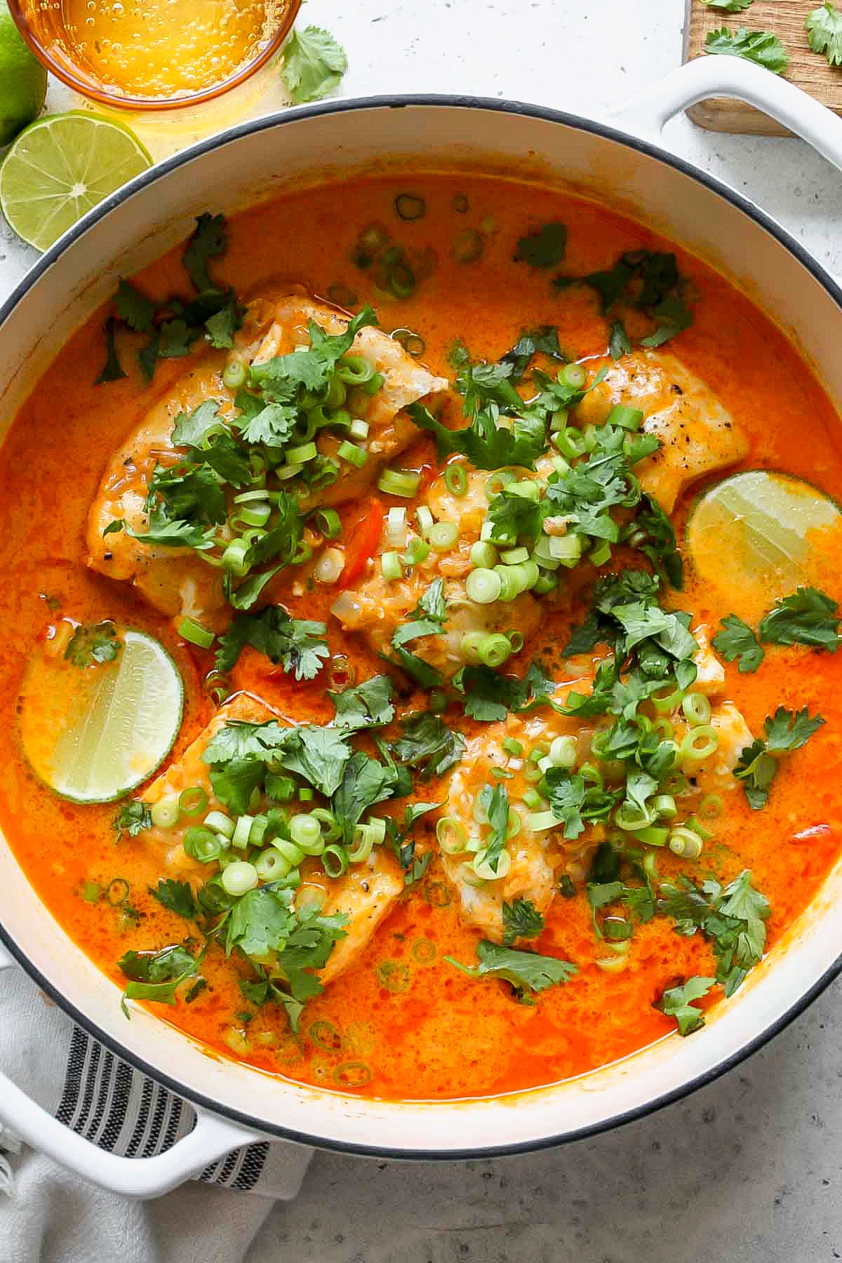 Thai Coconut Cod topped with cilantro and green onion in a large white sauté pan.