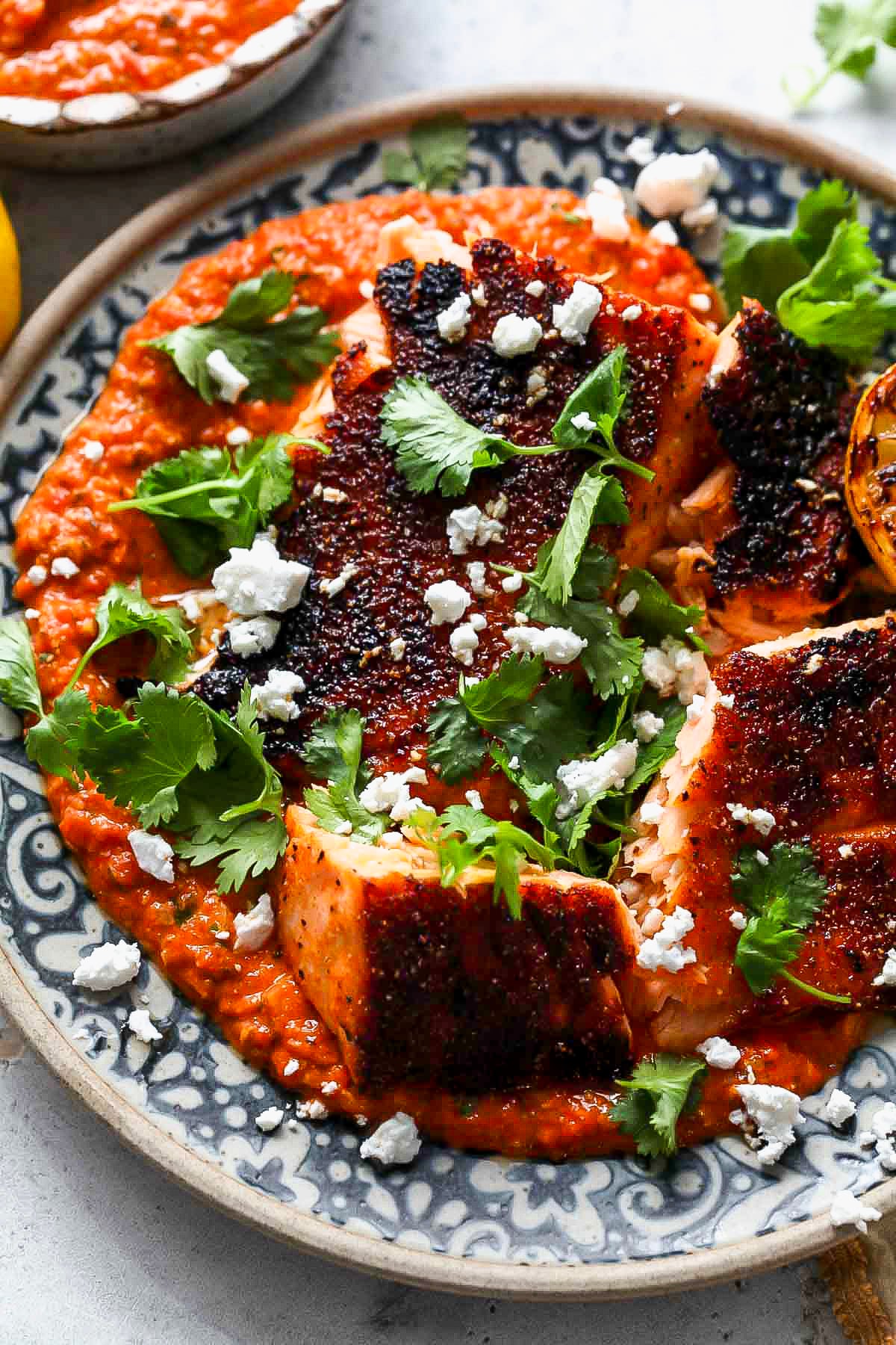 Chunks of broiled salmon arranged on a plate over pepita salsa with sprigs of cilantro.