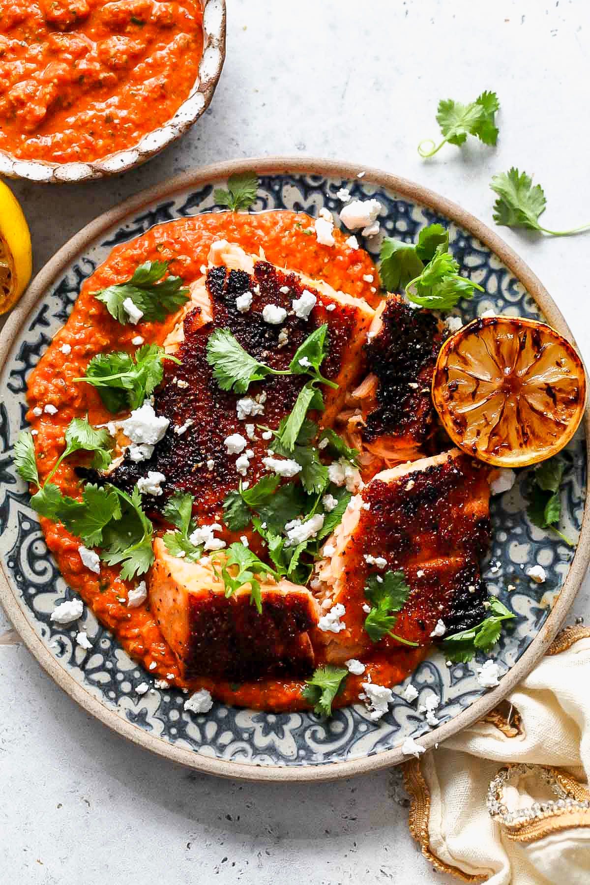 Broiled salmon arranged over pepita salsa on a blue and white patterned plate.