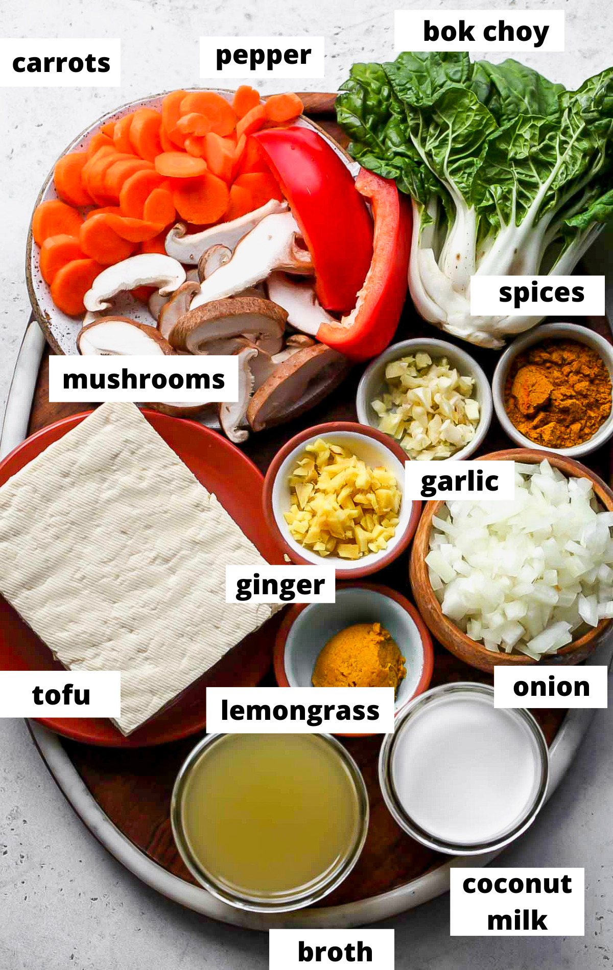 Recipe ingredients in separate bowls with labels arranged on a wooden serving platter.
