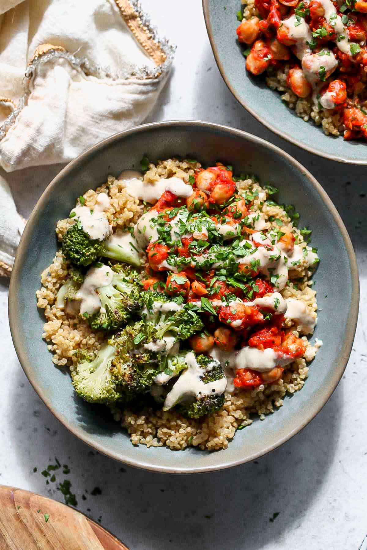 Chickpea and broccoli bowl topped with creamy garlic sauce styled in a blue bowl.