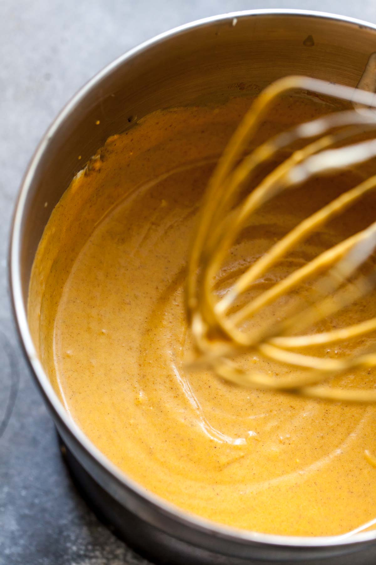 Pumpkin cheesecake filling being beaten in a stand mixer.
