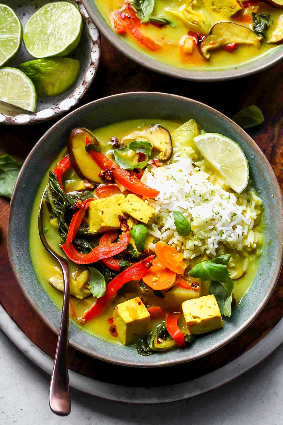 Thai vegetable soup in a blue serving bowl with a spoon resting on the left side.