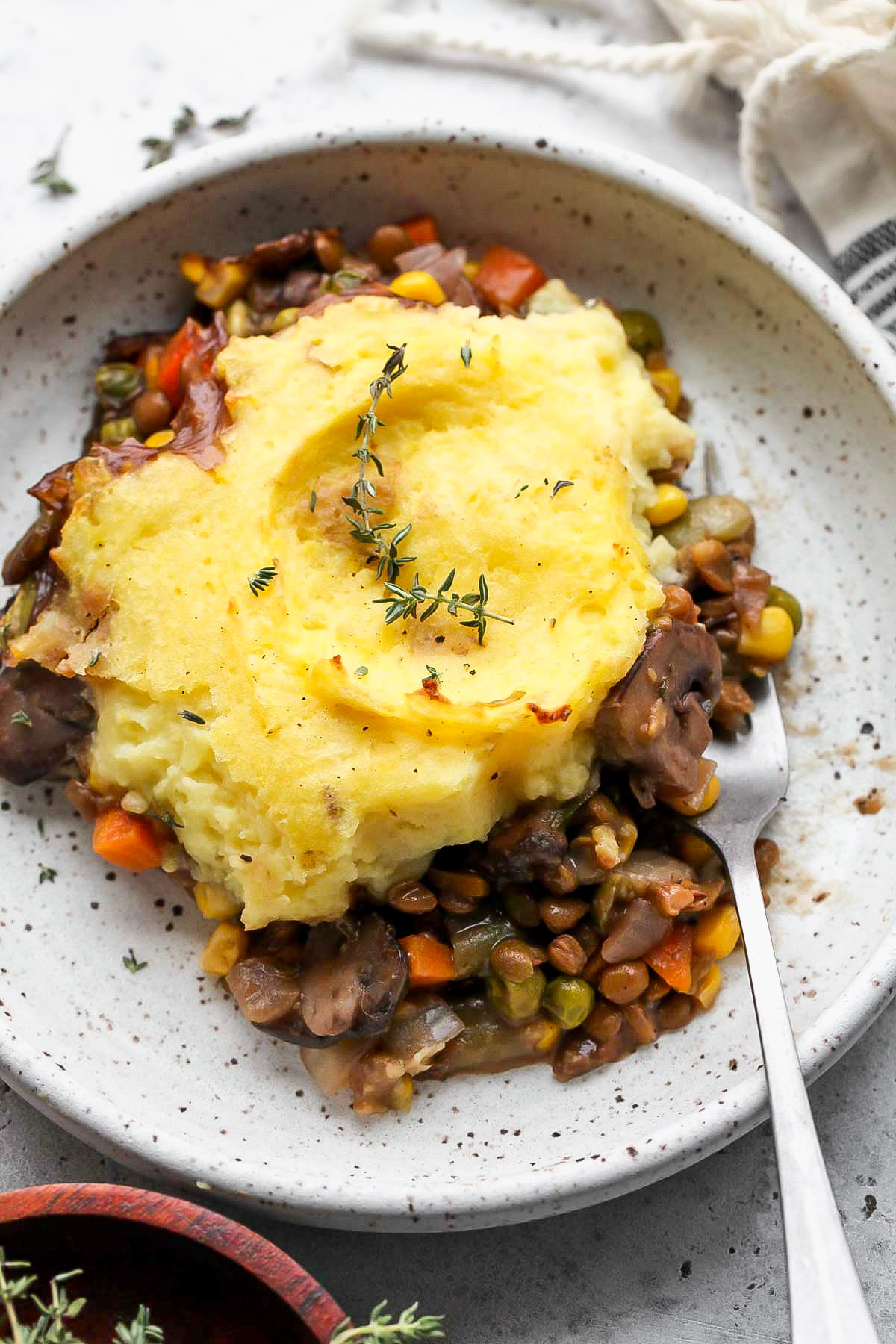 A serving of vegetarian shepherds pie served on a white speckled plate.