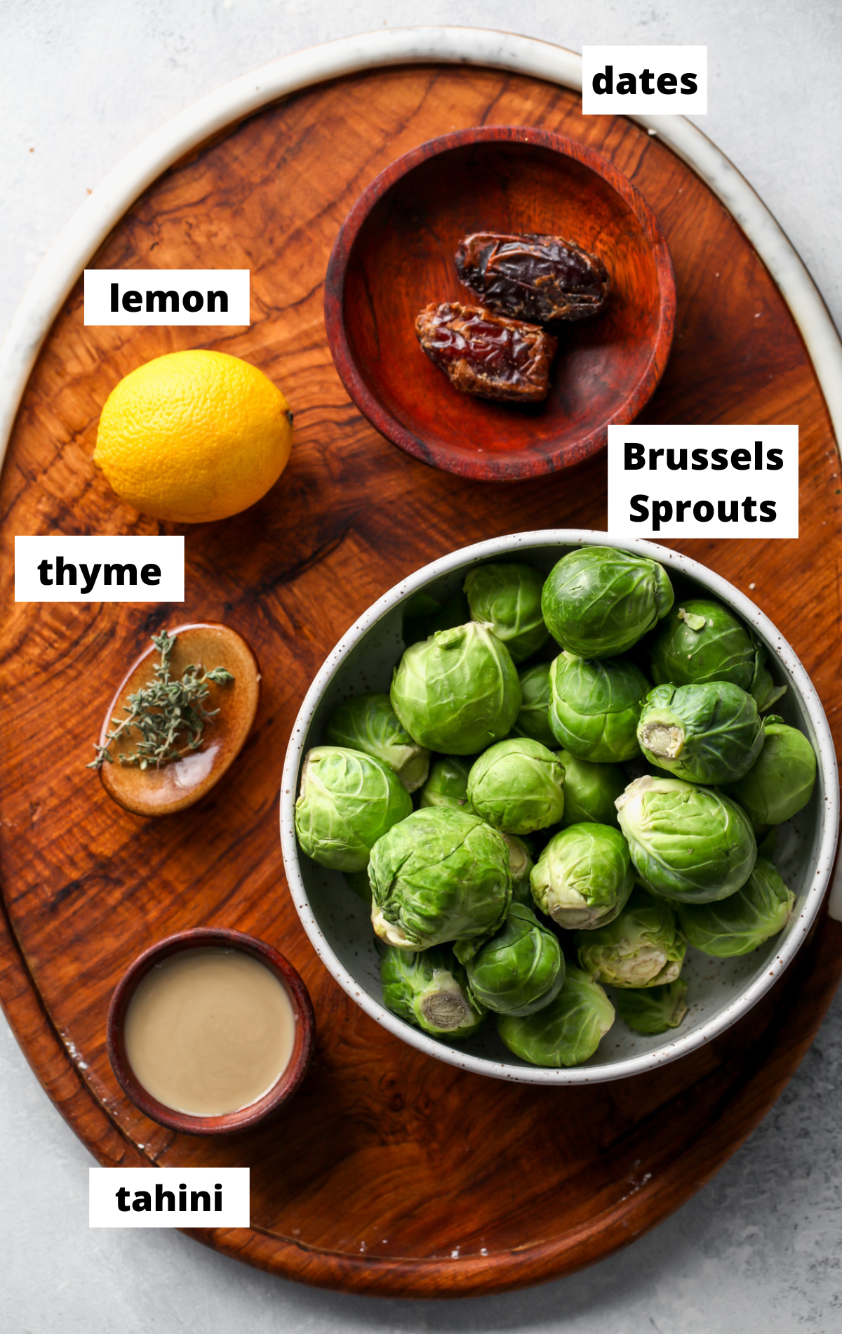 Ingredients in separate bowls on a wooden platter with labels.