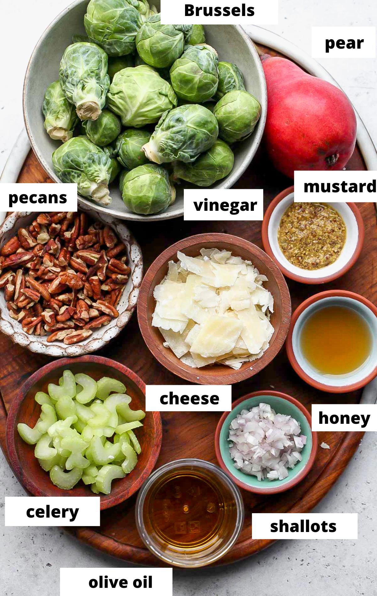 Recipe ingredients in separate bowls arranged on a wooden platter with labels.