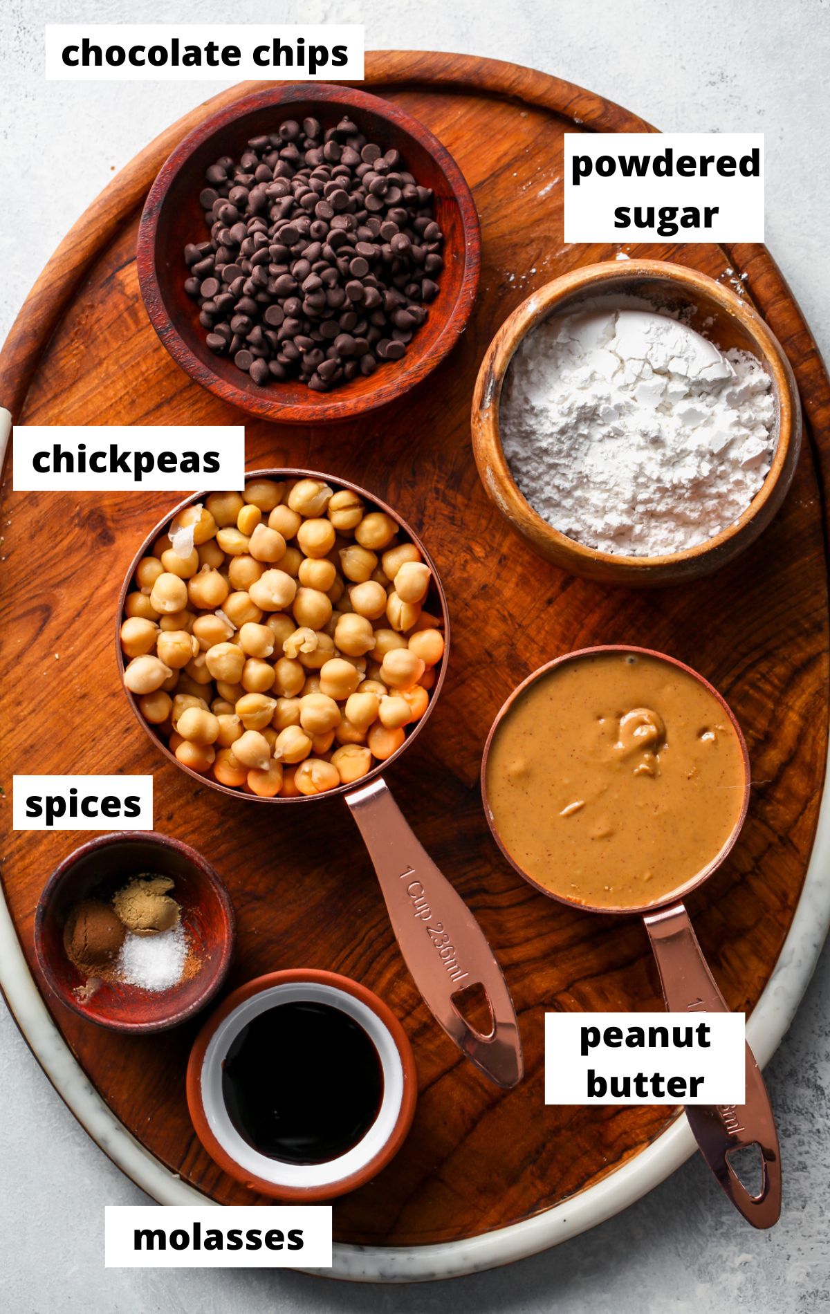 Recipe ingredients arranged in separate bowls on a wooden serving platter with labels.