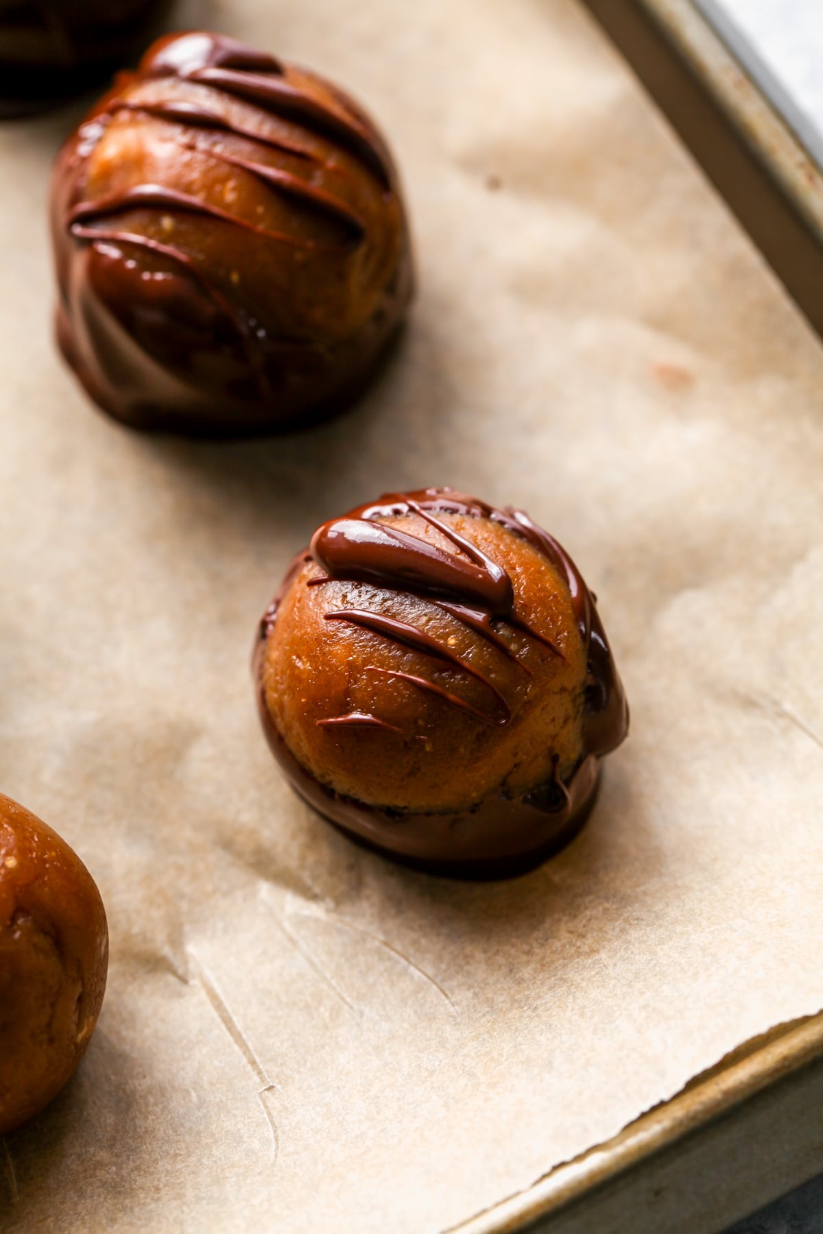 A Buckeye candy drizzled with chocolate on a piece of parchment paper waiting to firm up.