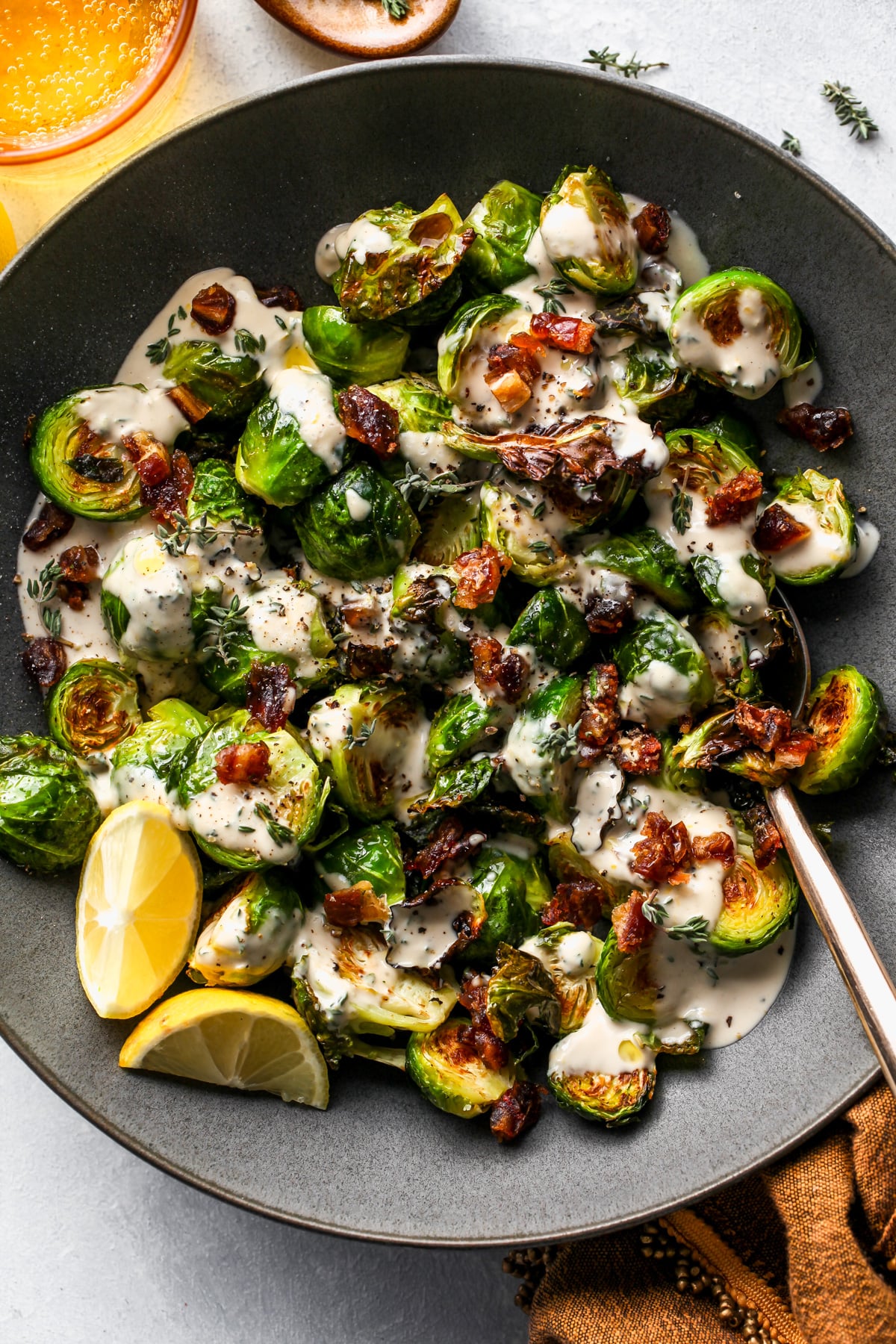 Tahini Brussels Sprouts assembled in a grey serving bowl with a spoon resting on the right side.