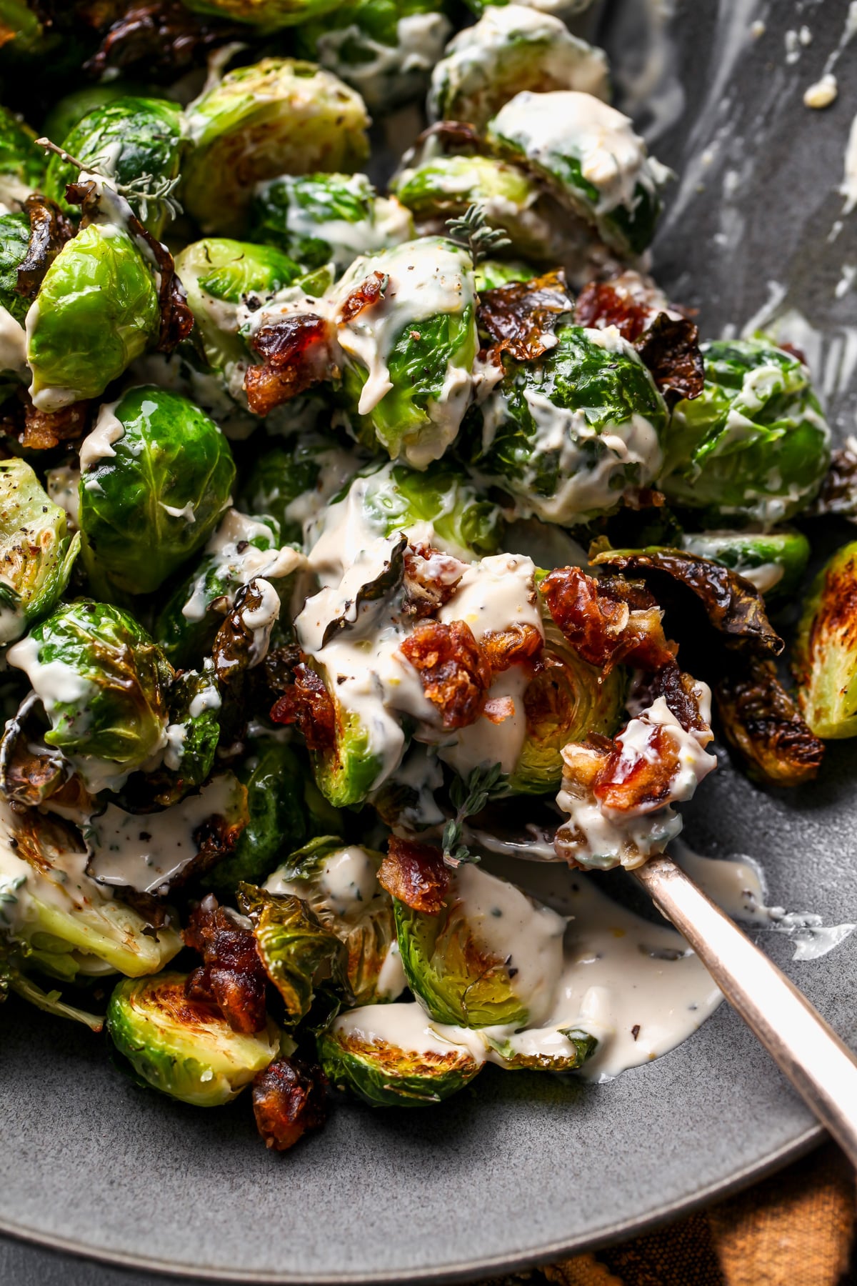 A serving spoon digging into a bowl of Brussels.