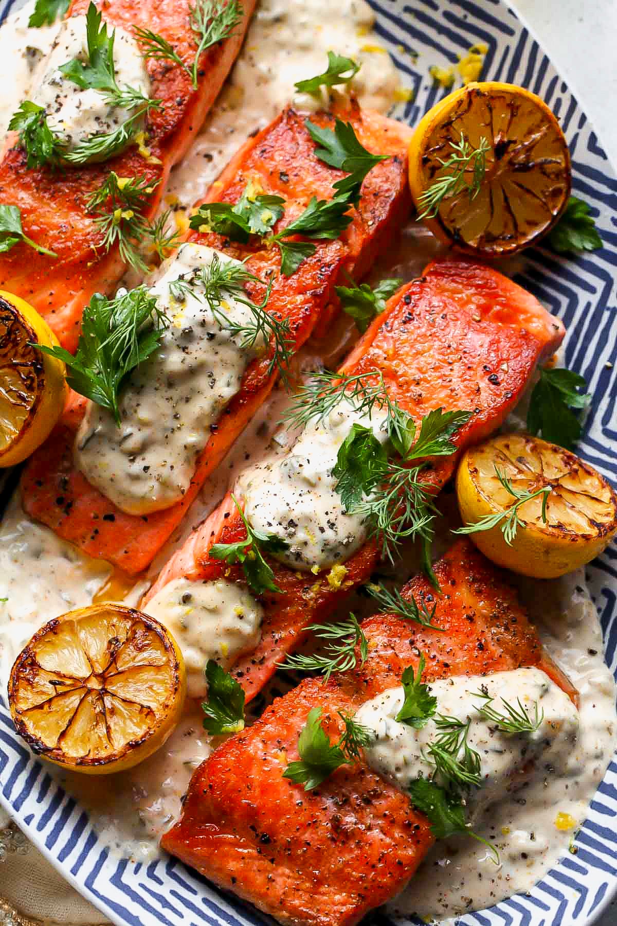 Pan-seared trout arranged on a blue and white platter topped with Old Bay Remoulade and herbs.