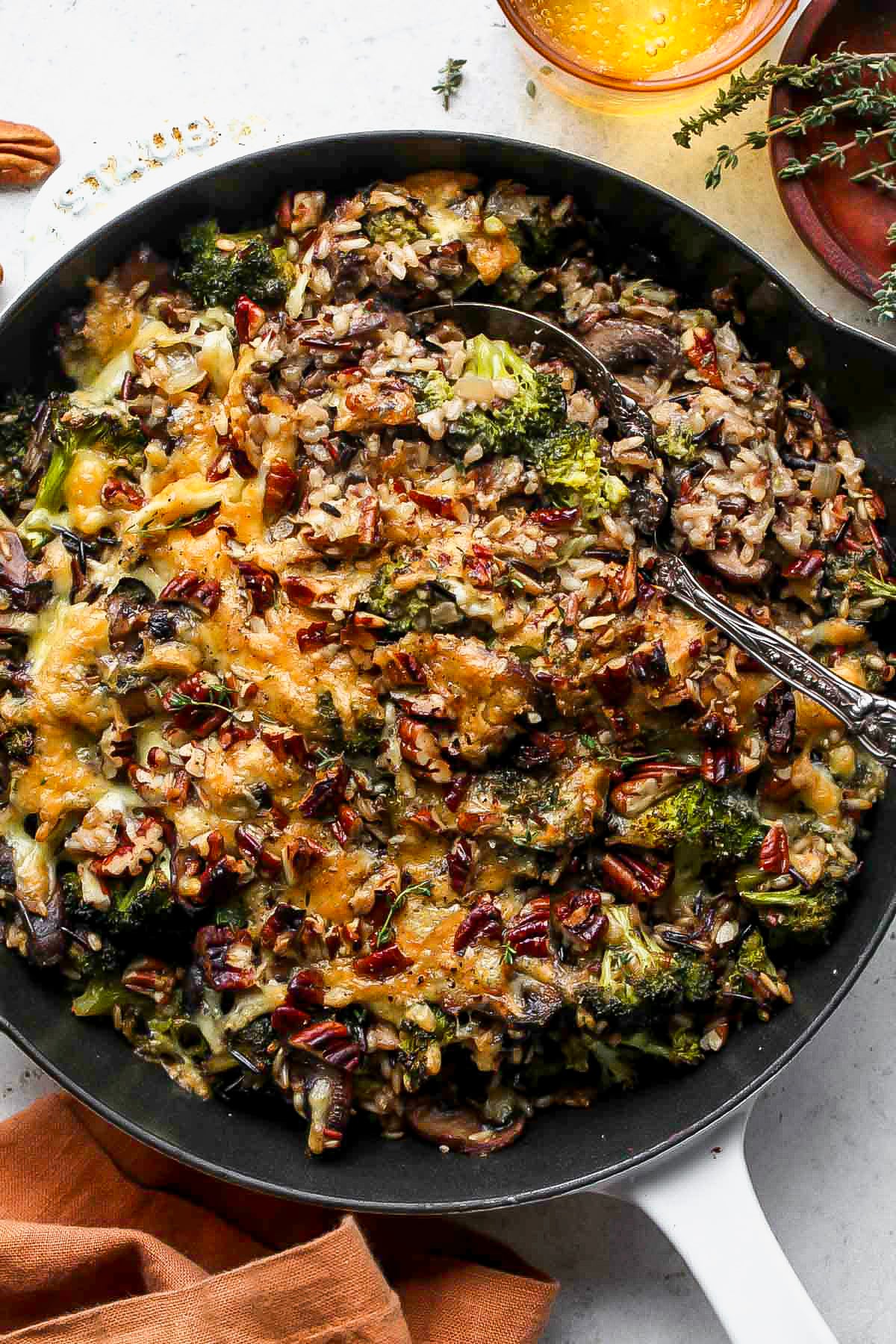 Wild rice casserole topped with pecans in a black cast iron skillet after baking.