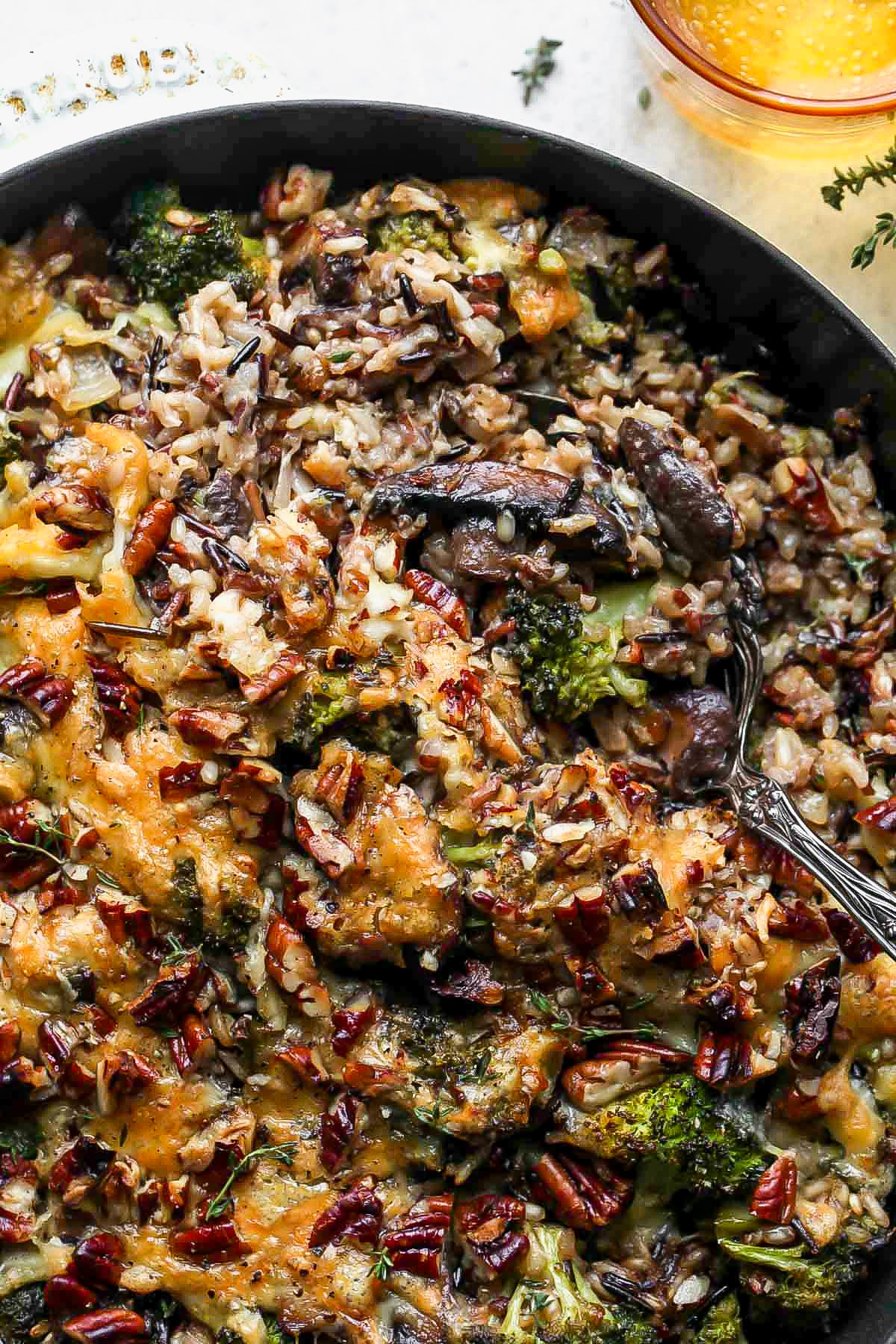 A serving spoon digging into a pan of wild rice casserole.