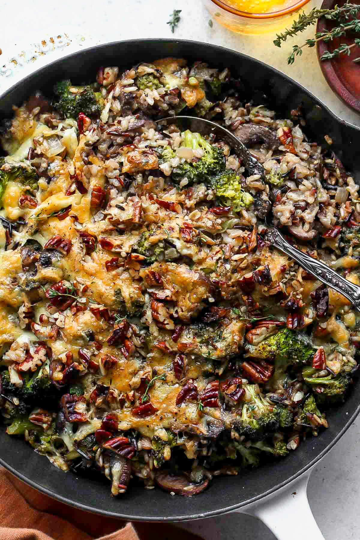 Wild rice casserole in a black pan with a serving spoon resting on the right side.