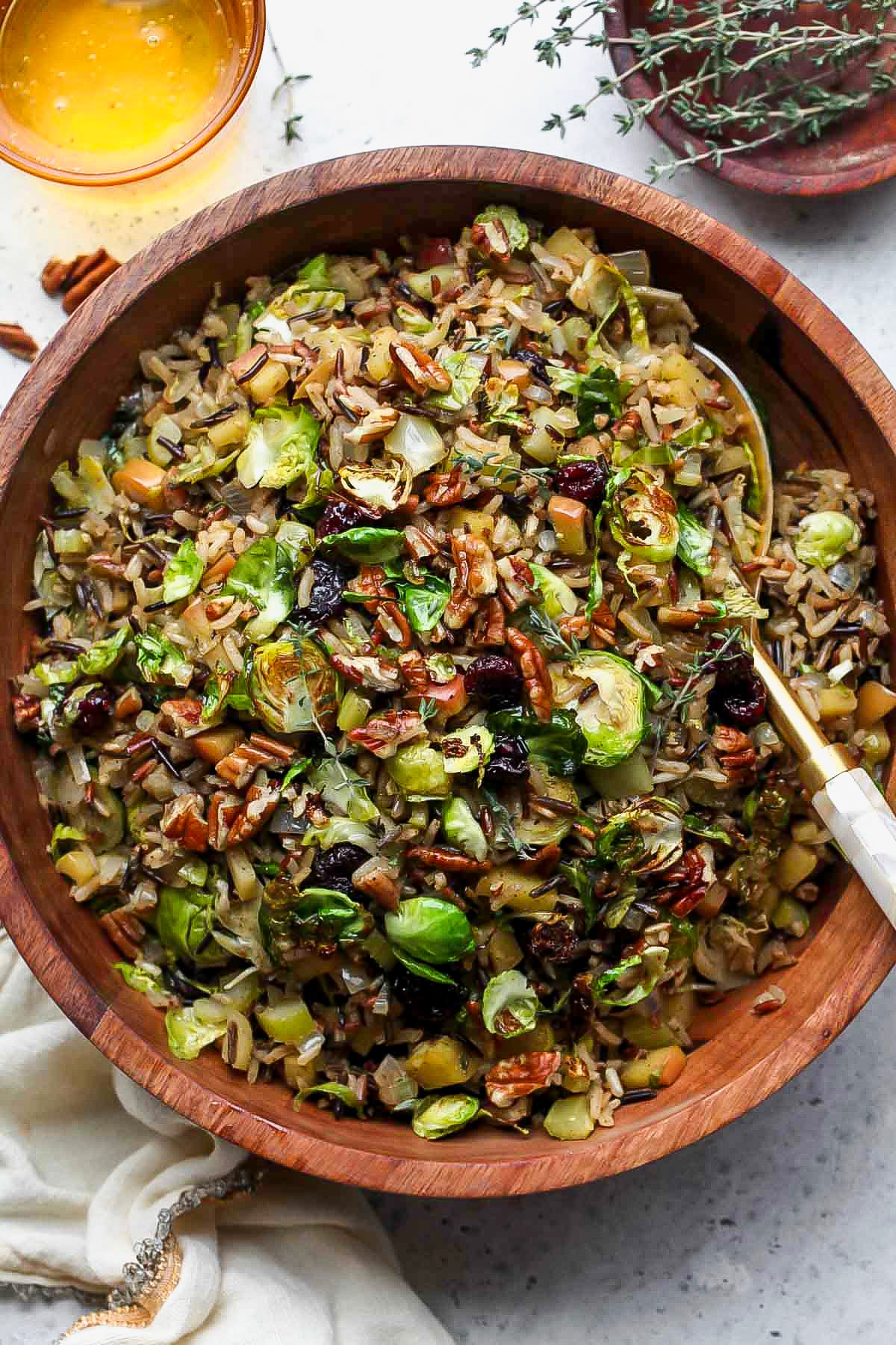 Wild Rice Pilaf styled in a wooden serving bowl with a serving spoon resting on the right side.