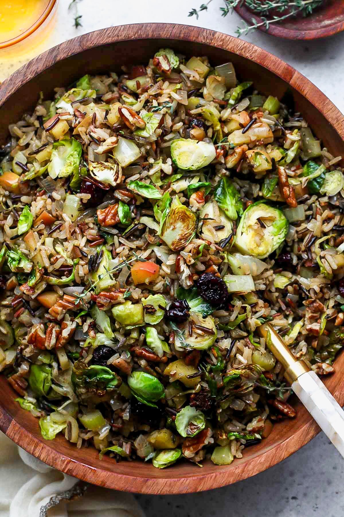 Wild rice pilaf being tossed in a large wooden serving bowl.