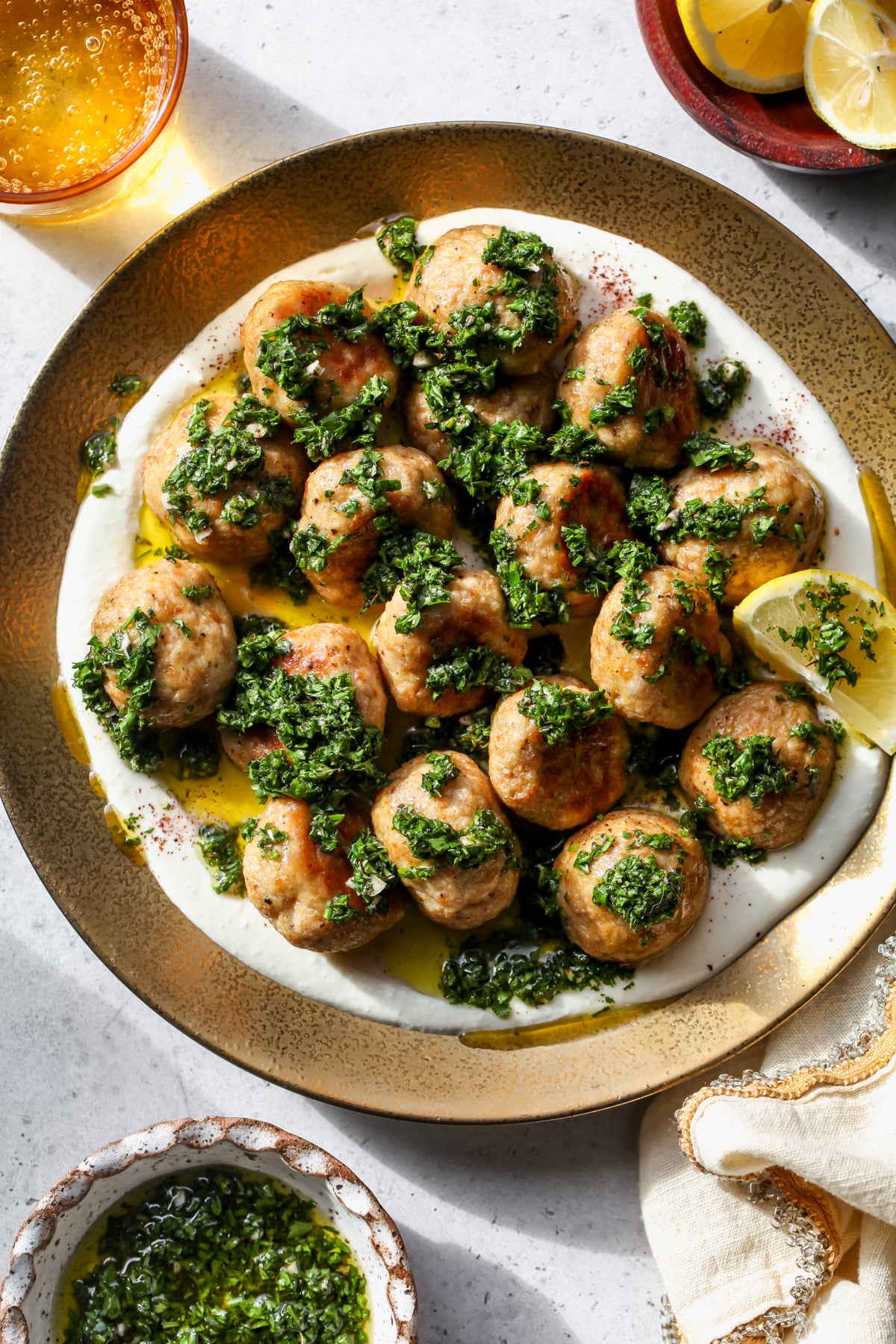 Chimichurri chicken meatballs over feta cream topped with chimichurri on a gold plate.