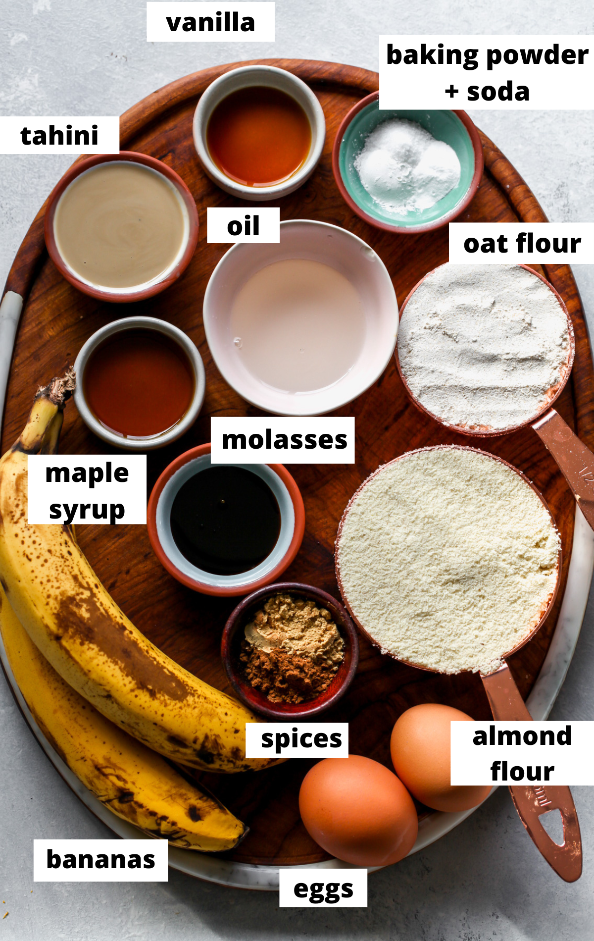 Recipe ingredients in separate bowls with labels on a wooden platter.