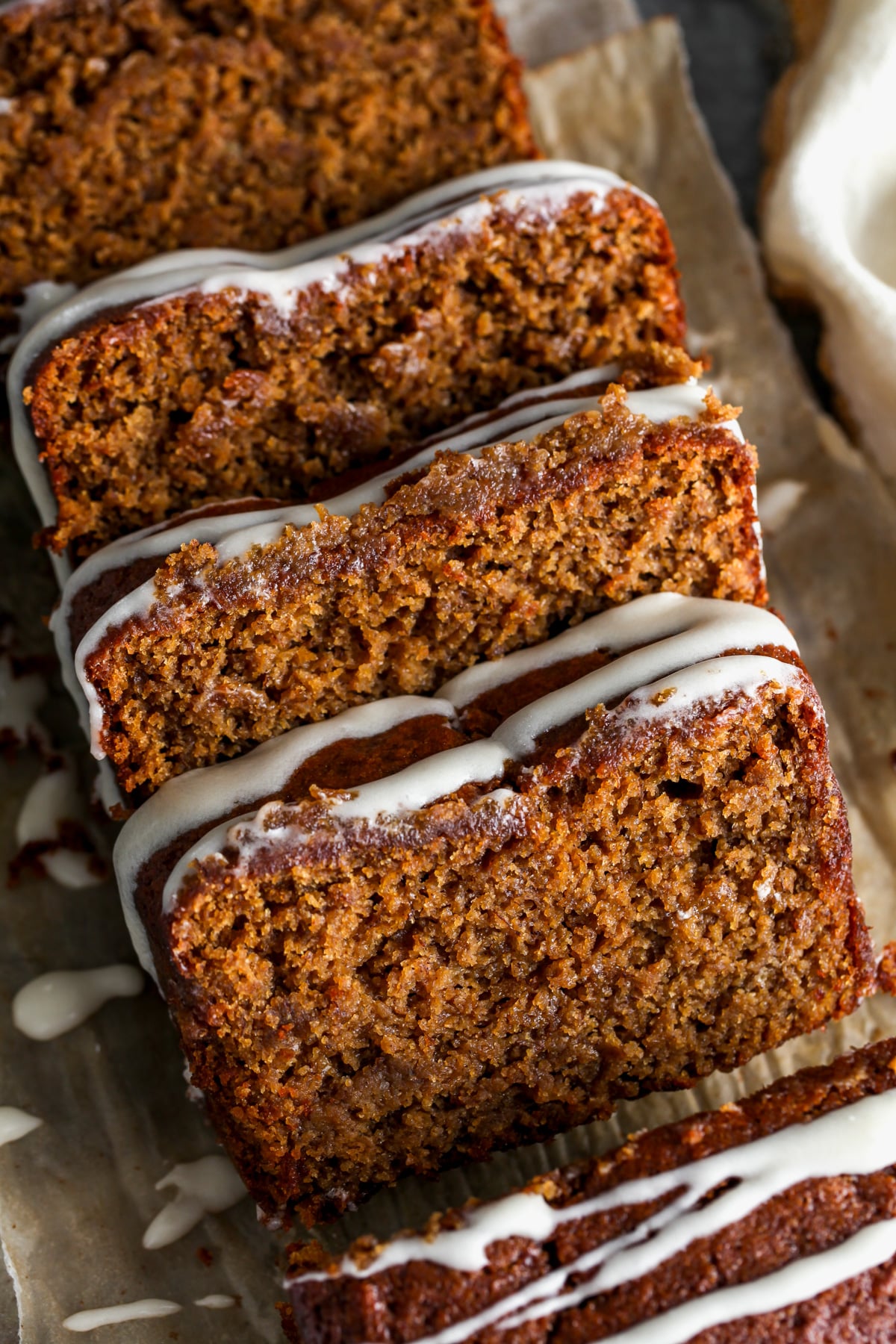 A loaf of gingerbread banana bread being sliced into pieces on a cutting board.