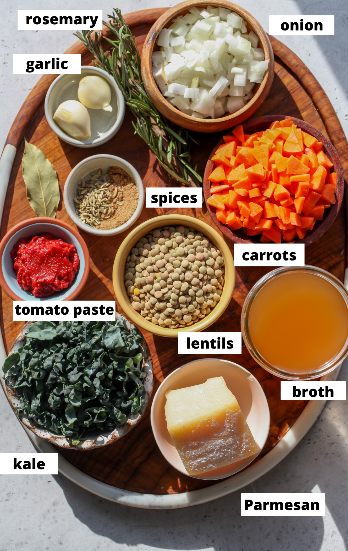Recipe ingredients in separate bowls arranged on a wooden platter with labels.