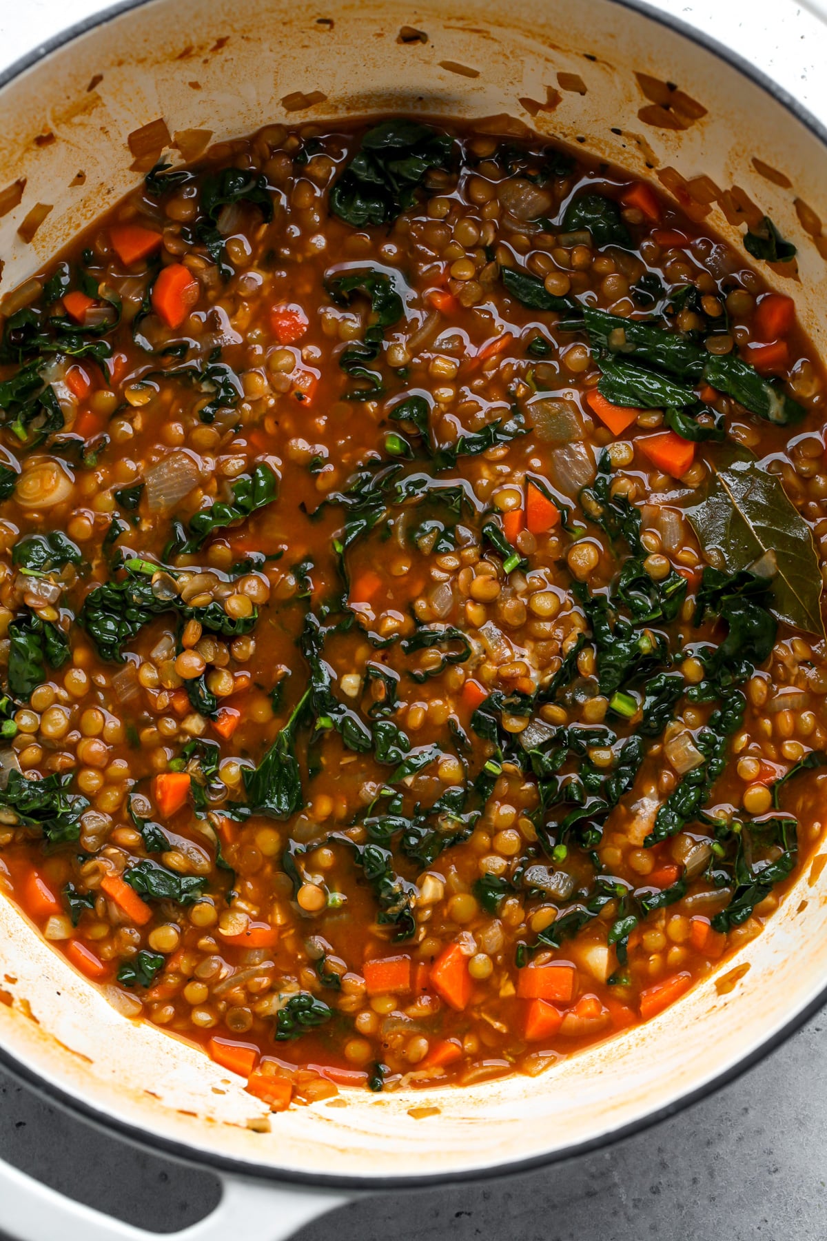 A white Dutch oven filled with the best lentil soup recipe.