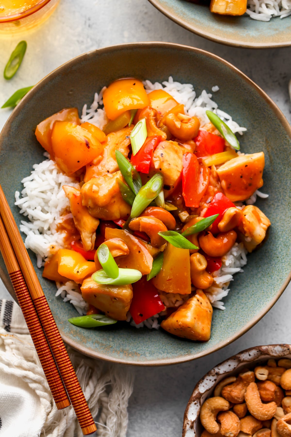 Sweet and sour chicken served over rice in a blue bowl with chopsticks resting on the left side.